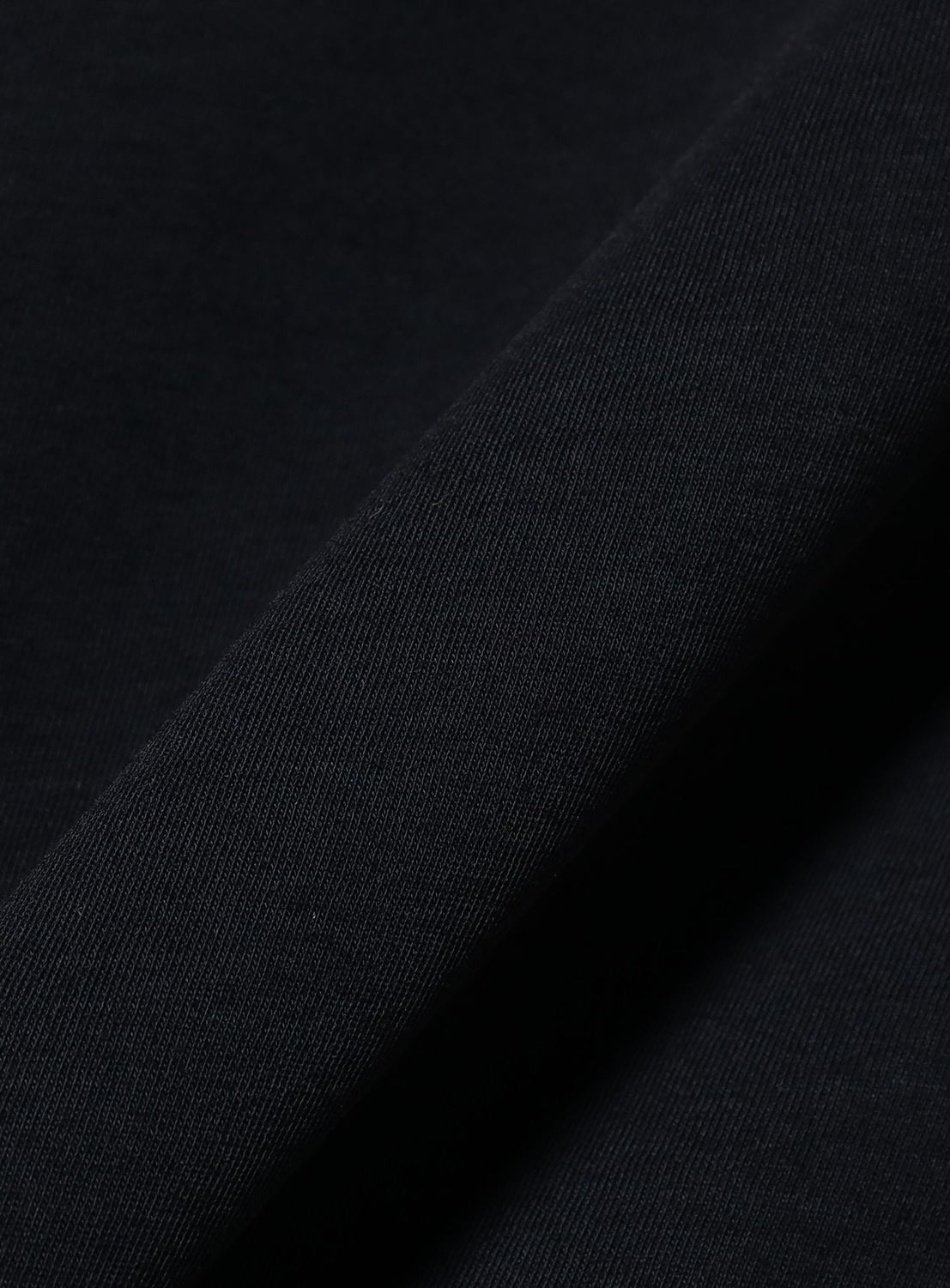 Close-up of a folded piece of black Japanese fabric with a soft texture and visible weave pattern, creating diagonal lines and subtle shading—ideal for crafting the BEAMS Relaxed Fit Heat Protection T-Shirt.