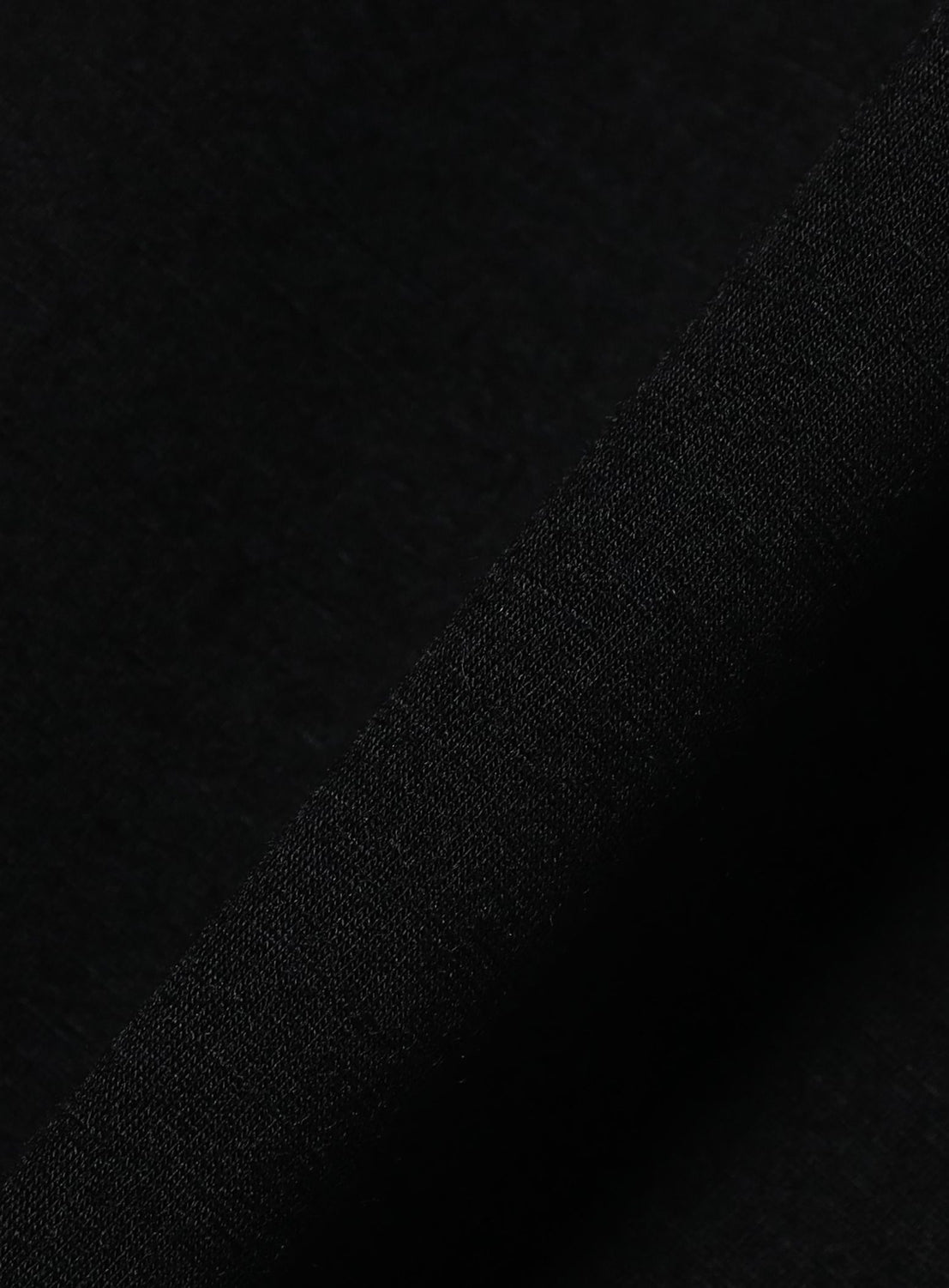 A close-up of BEAMS' the A - Washable Merino Wool Sleeveless Top in black, revealing the textured weave and minimalist design of its merino wool fabric under gentle lighting.