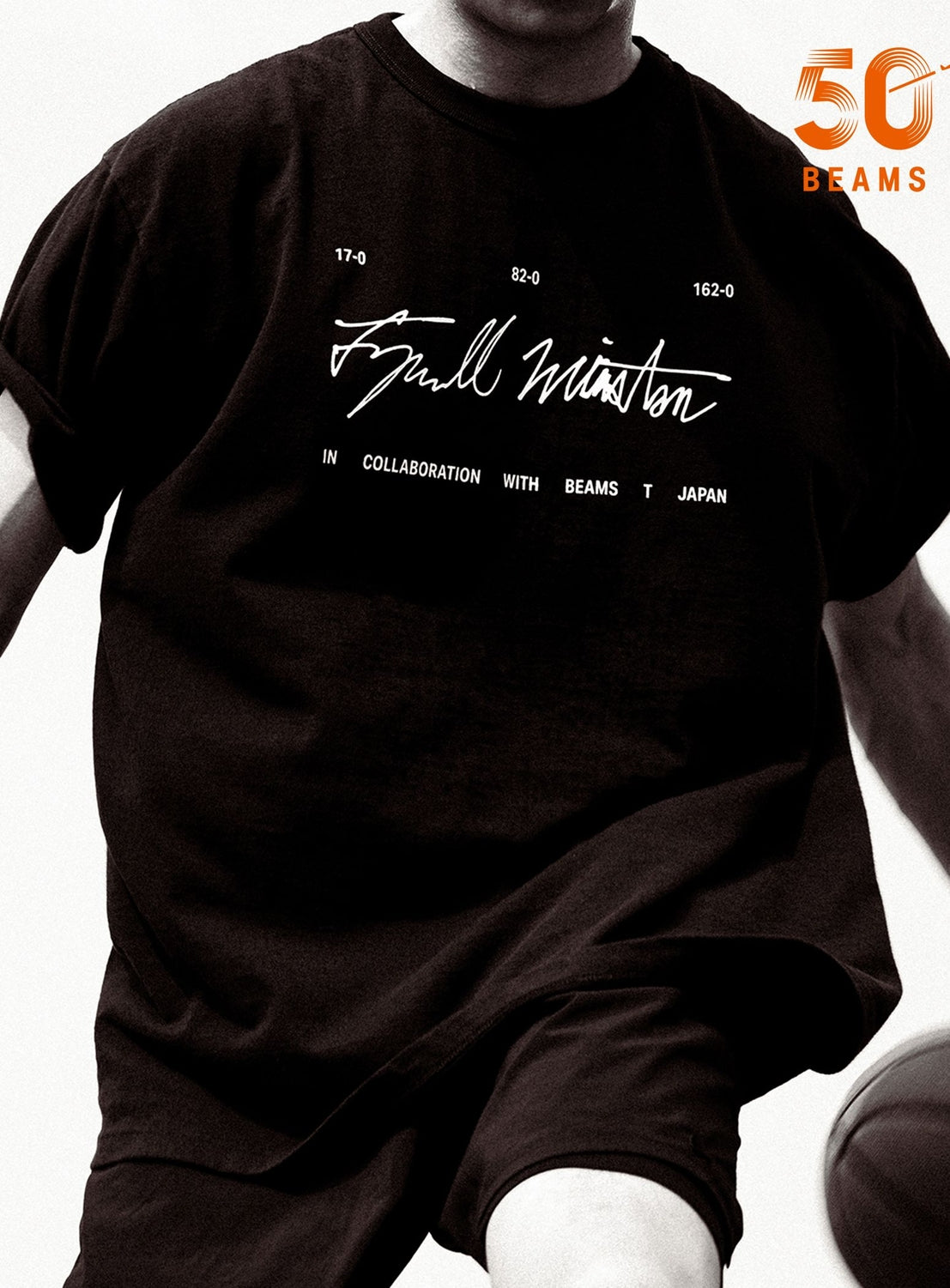 A person wearing the BEAMS T Tyrrell Winston - Sign T-Shirt in black, featuring white signature graphics and text such as “IN COLLABORATION WITH BEAMS T JAPAN” and a reference to Tyrrell Winston, with an orange “50 BEAMS” logo displayed in the upper right corner.