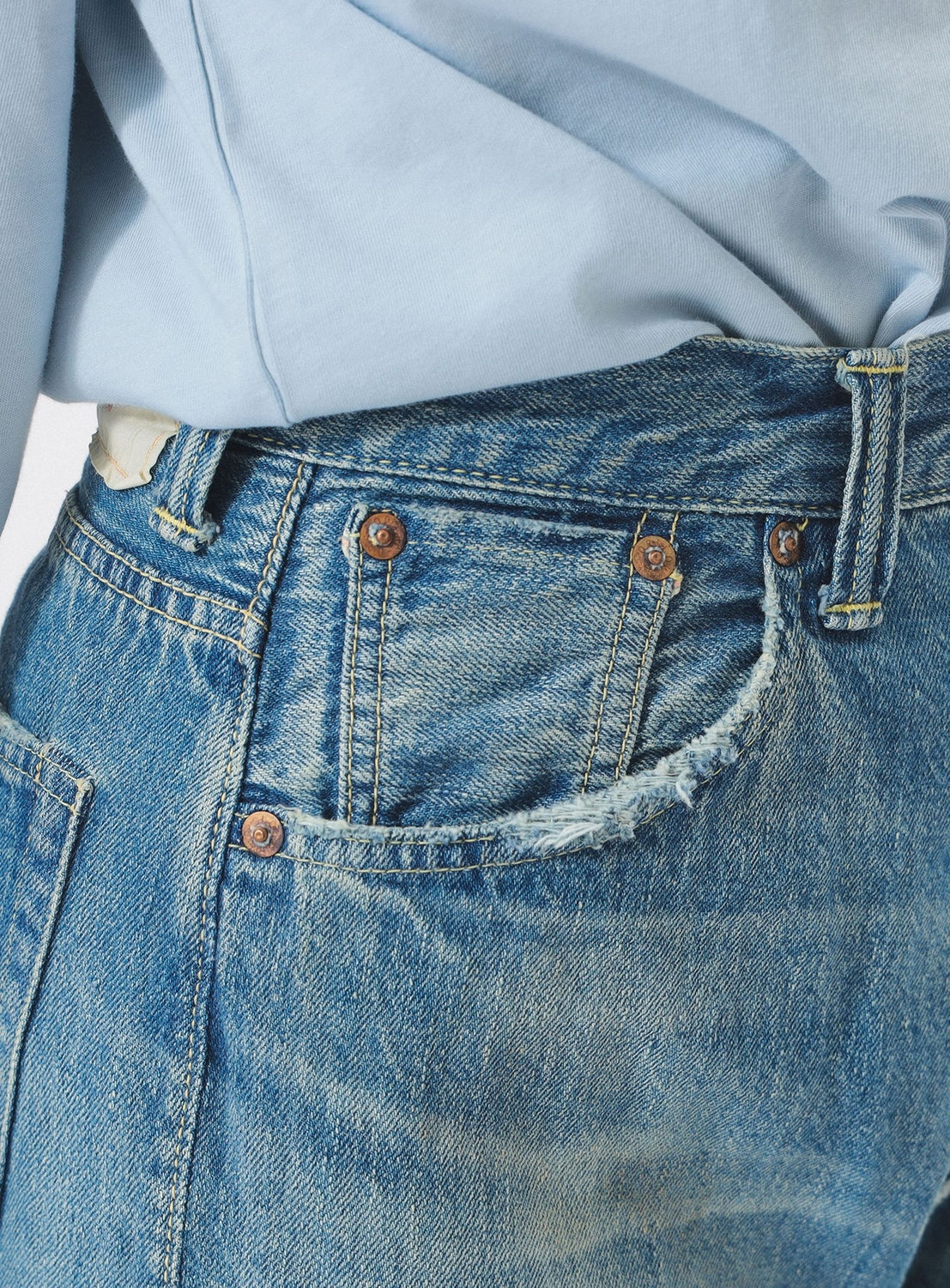 Close-up of blue jeans with a light blue shirt underneath
