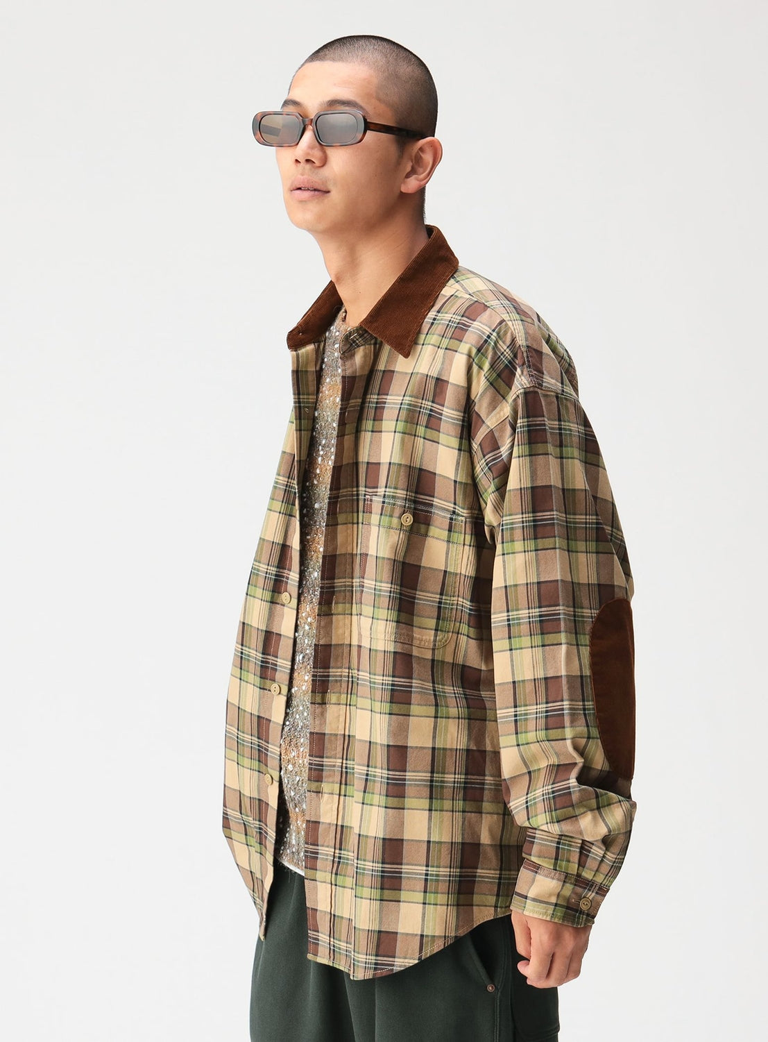 A person wearing a BEAMS Classic Check Work Shirt with a brown corduroy collar, elbow patches, and dark rectangular sunglasses.