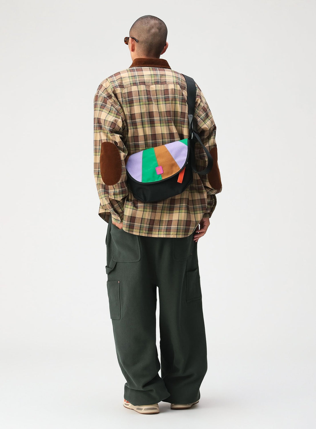 A person seen from behind wears a BEAMS Classic Check Work Shirt, featuring a tan plaid pattern, brown elbow patches, a corduroy collar, and a multicolored crossbody bag.