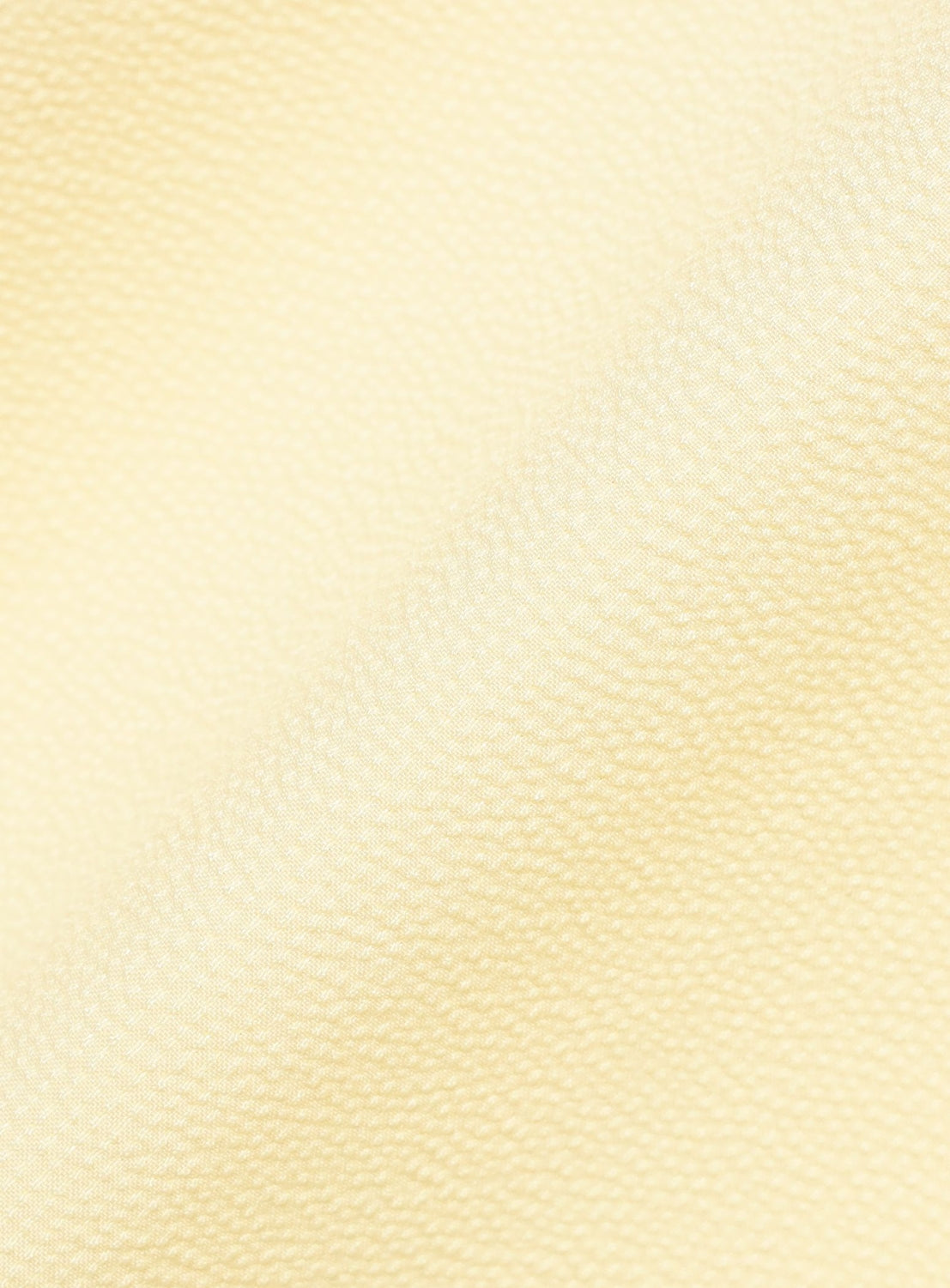 A close-up of the BEAMS Stretch Quick-Dry Seersucker Relaxed Fit Shirt in light cream shows the textured fabric's distinctive puckered surface, with a diagonal fold casting gentle shadows—highlighting the shirt’s lightweight and wrinkle-resistant seersucker material.