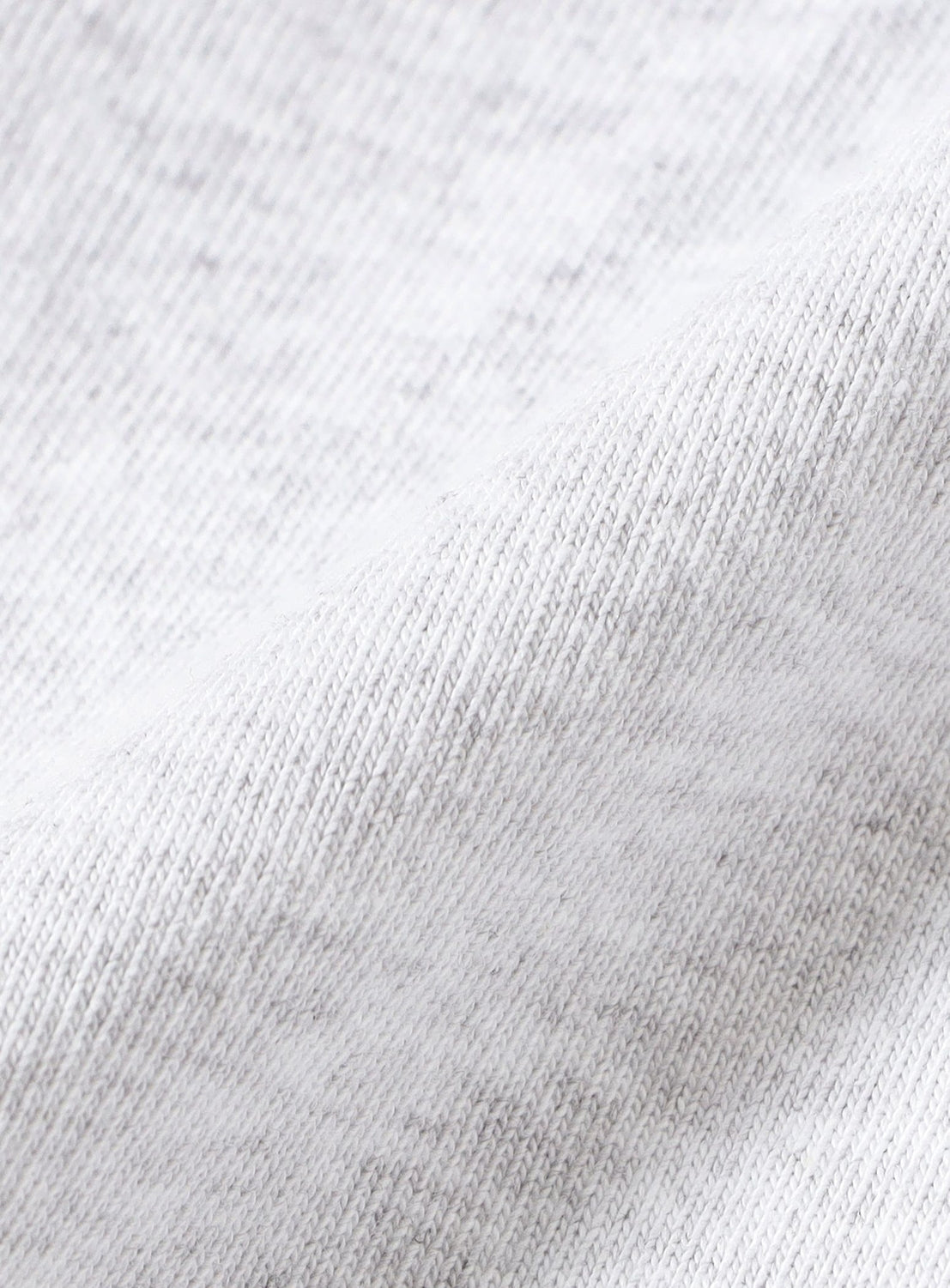 Close-up of the light gray, textured fabric from the Tyrrell Winston - Win T-Shirt by BEAMS T, showing a subtle diagonal fold that accentuates the weave and softly heathered surface of the material.