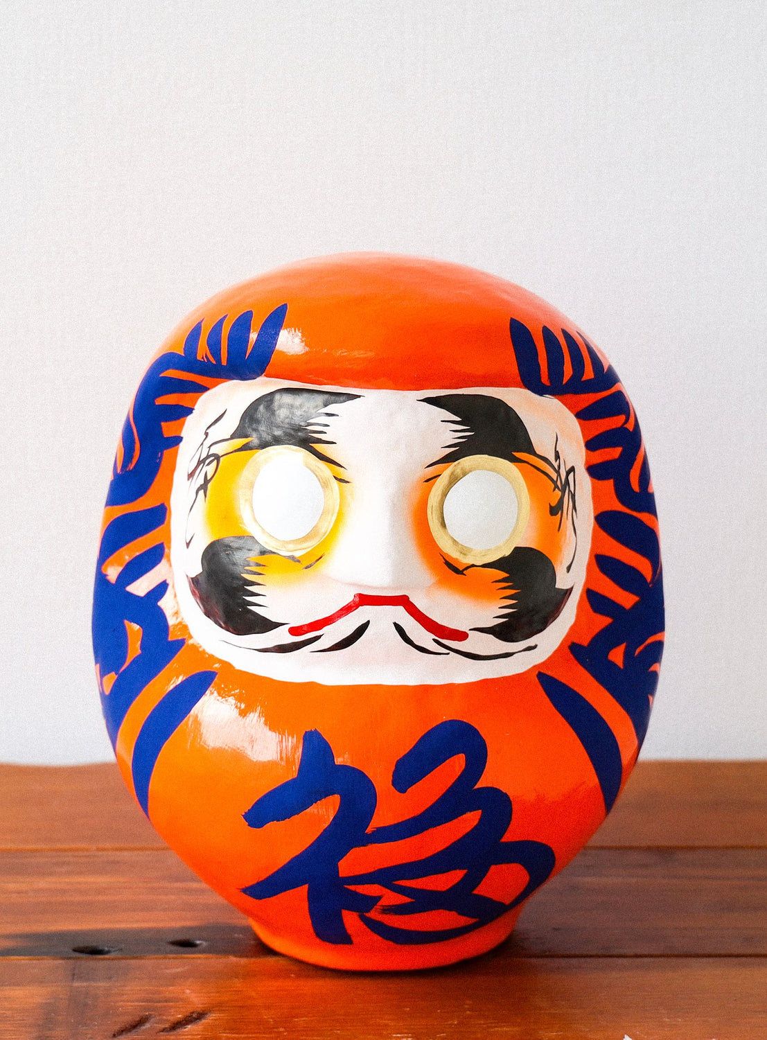 Traditional Japanese daruma doll with an orange background