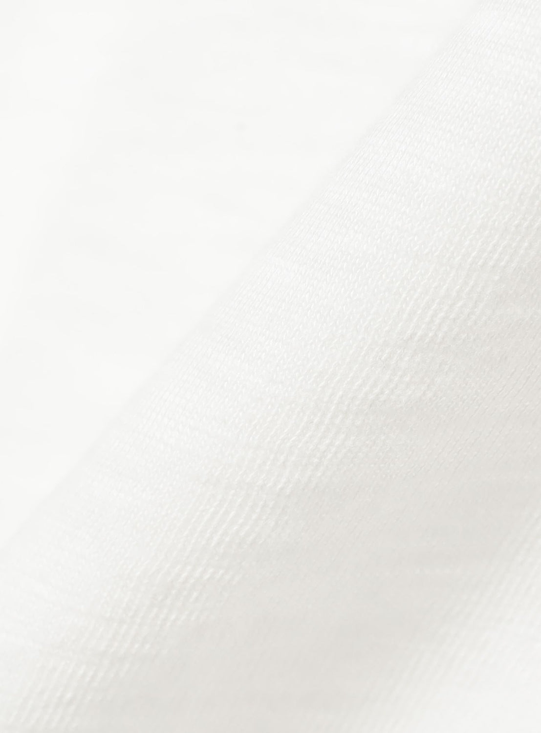 Close-up of the Preppy Dog Graphic T-Shirt by BEAMS BOY, highlighting its white, textured cotton fabric with a diagonal fold that showcases the weave and soft surface—a vintage-inspired material blending comfort with timeless appeal.