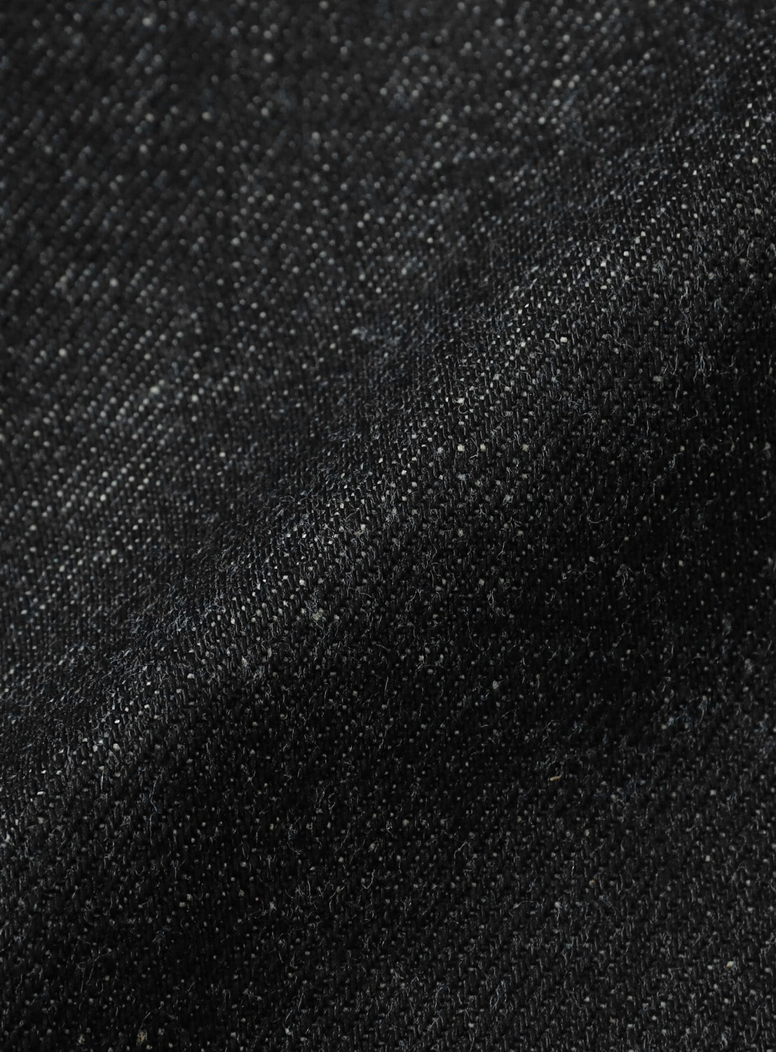 Close-up of heavyweight denim fabric from the SUGARHILL Classic Double Knee Denim Pants, highlighting its texture, weave, and fine white flecks, with a soft fold running diagonally through the image.