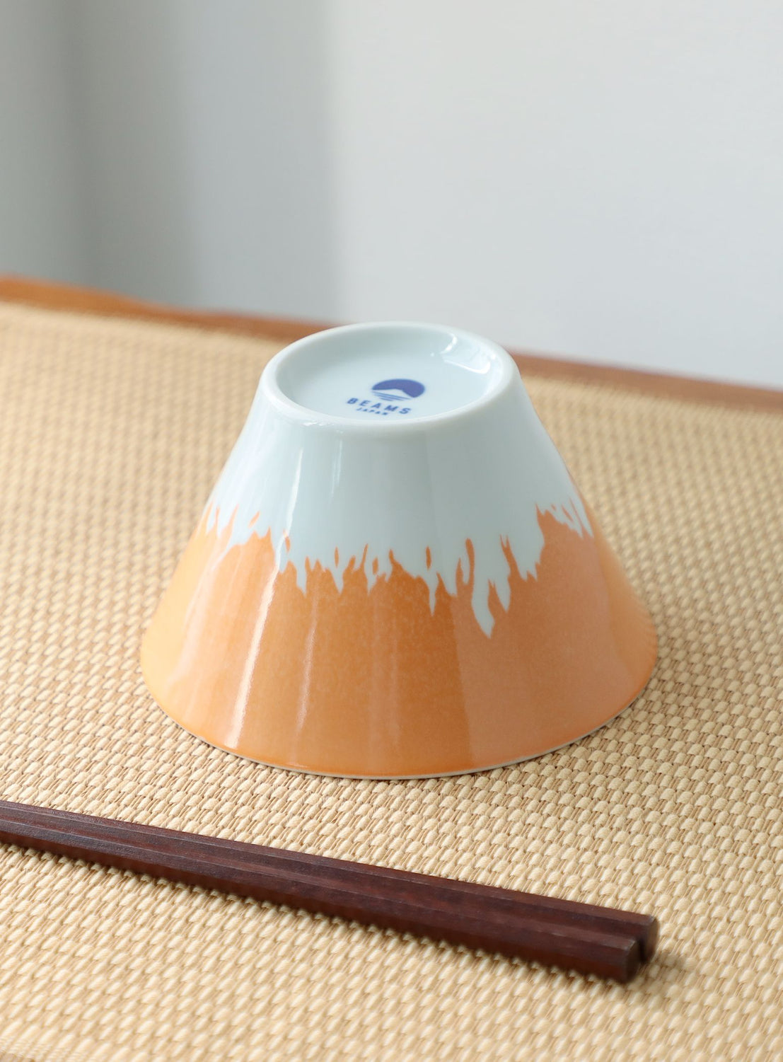 Ceramic bowl with gradient design on a textured surface with chopsticks.