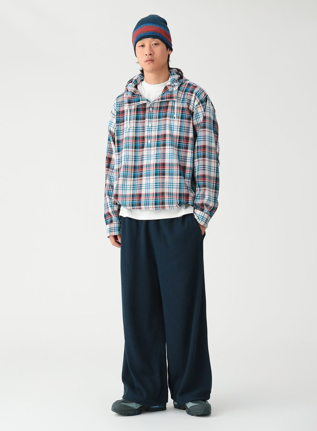 A person wearing a BEAMS Check Hooded Shirt over a white t-shirt, paired with dark wide-leg trousers, a beanie, and sneakers.