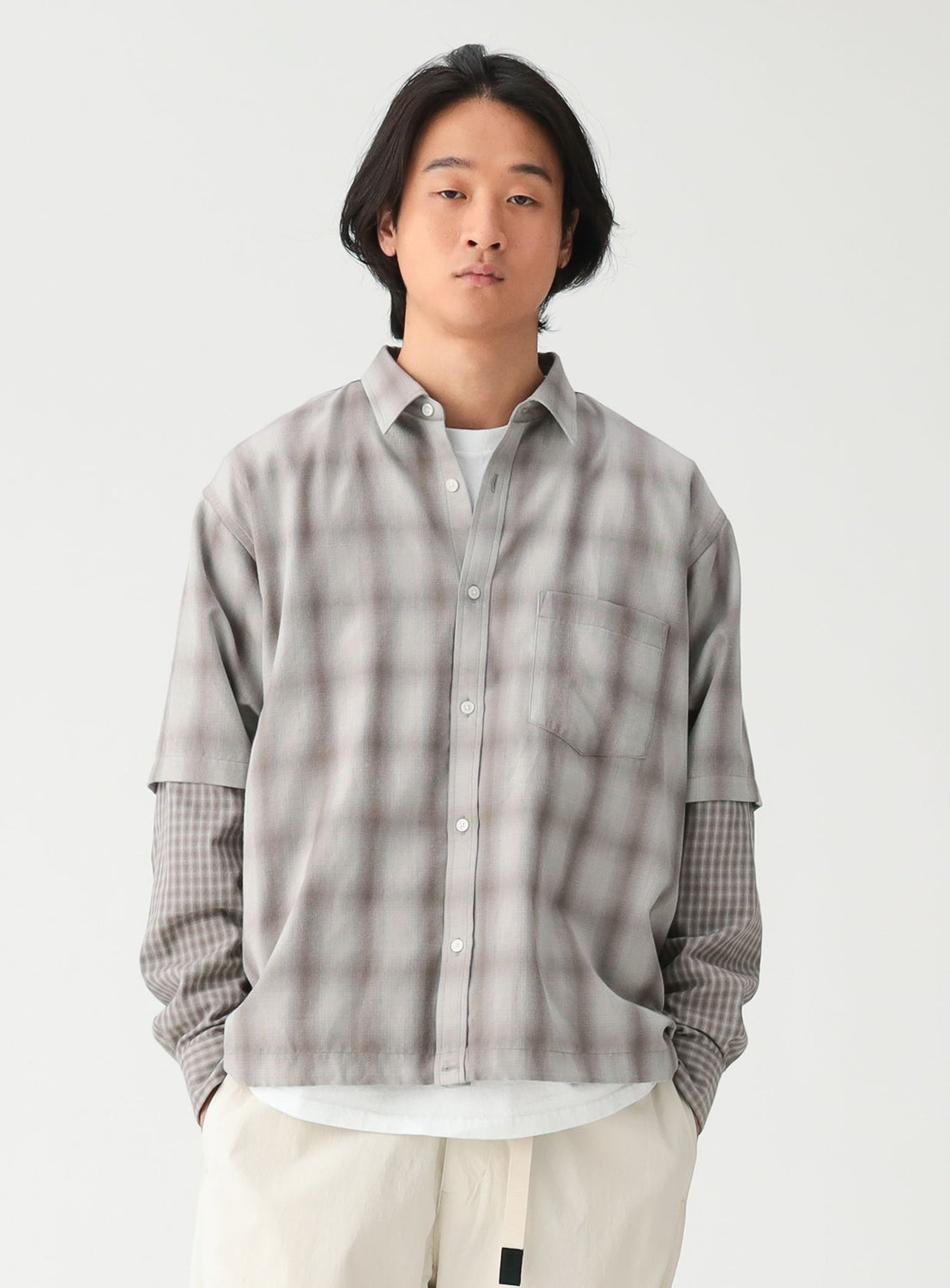 A person wearing a wide-fit, grey and white plaid BEAMS Layered Check Shirt over a white t-shirt.