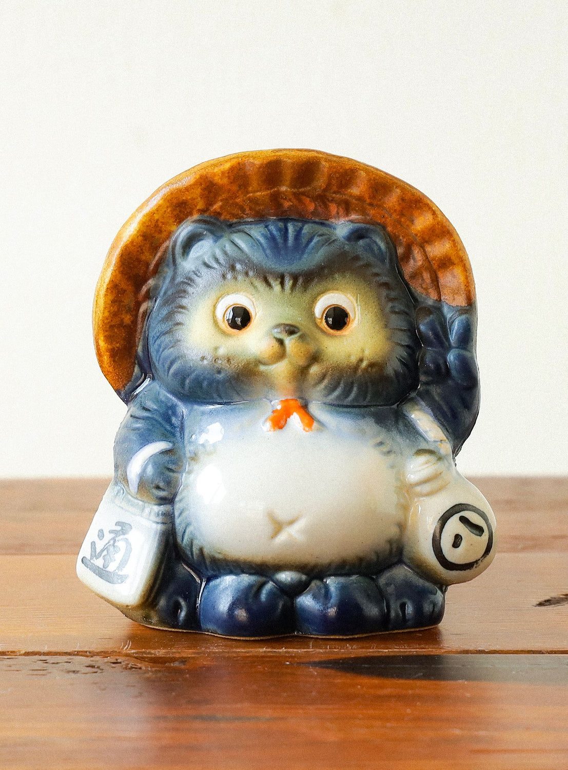 Ceramic figurine of a hedgehog with a straw hat on a wooden surface