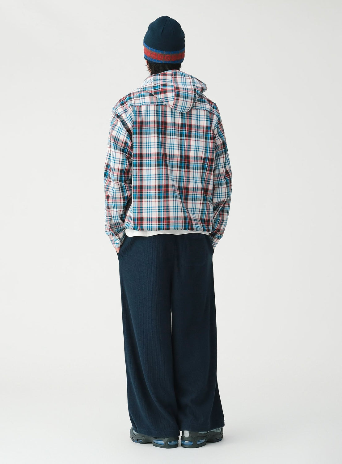 A person seen from behind, wearing a BEAMS Check Hooded Shirt, dark wide-leg trousers, and a beanie.