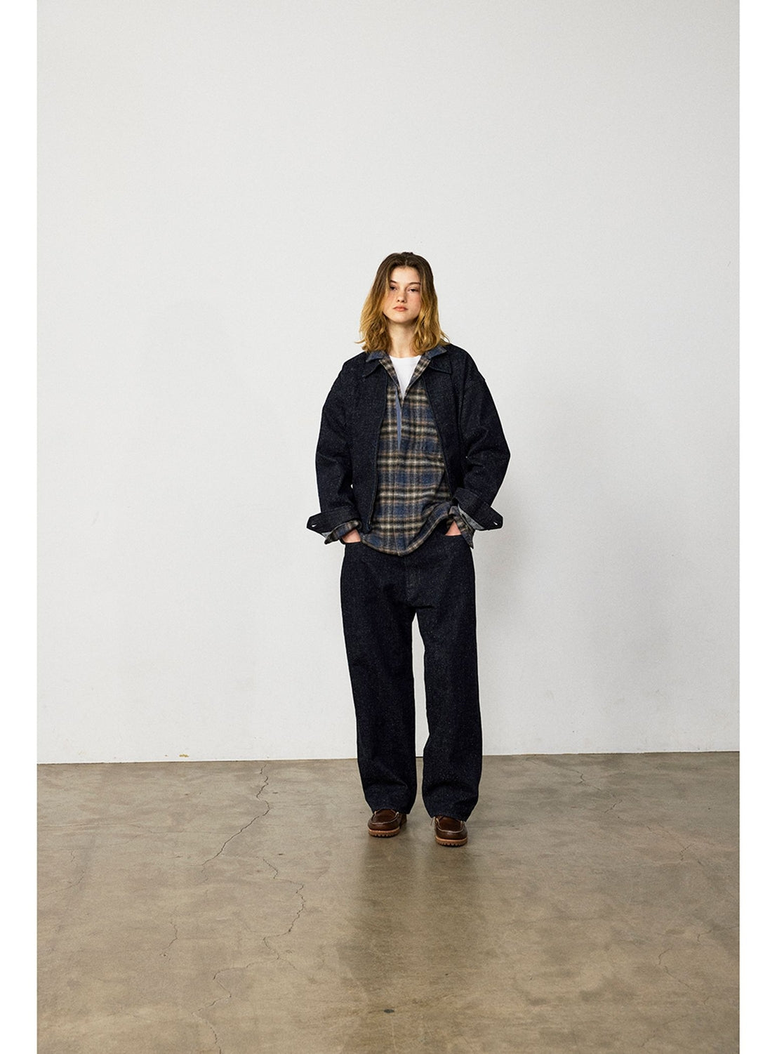 A person wearing a BEAMS Nep Denim Zip Jacket in dark nep denim, a plaid button-up shirt, and matching wide-fit trousers.