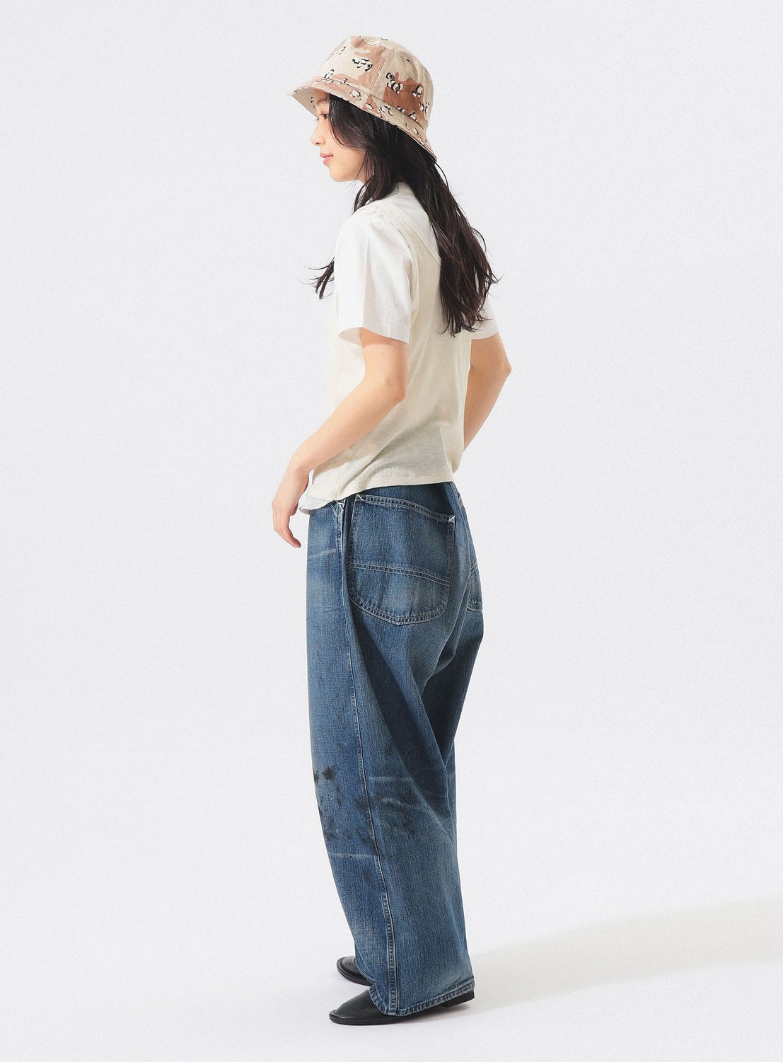 A woman wearing the BEAMS BOY Layered Rib Tank Top, wide-leg blue jeans, and a printed bucket hat stands sideways against a plain white background.