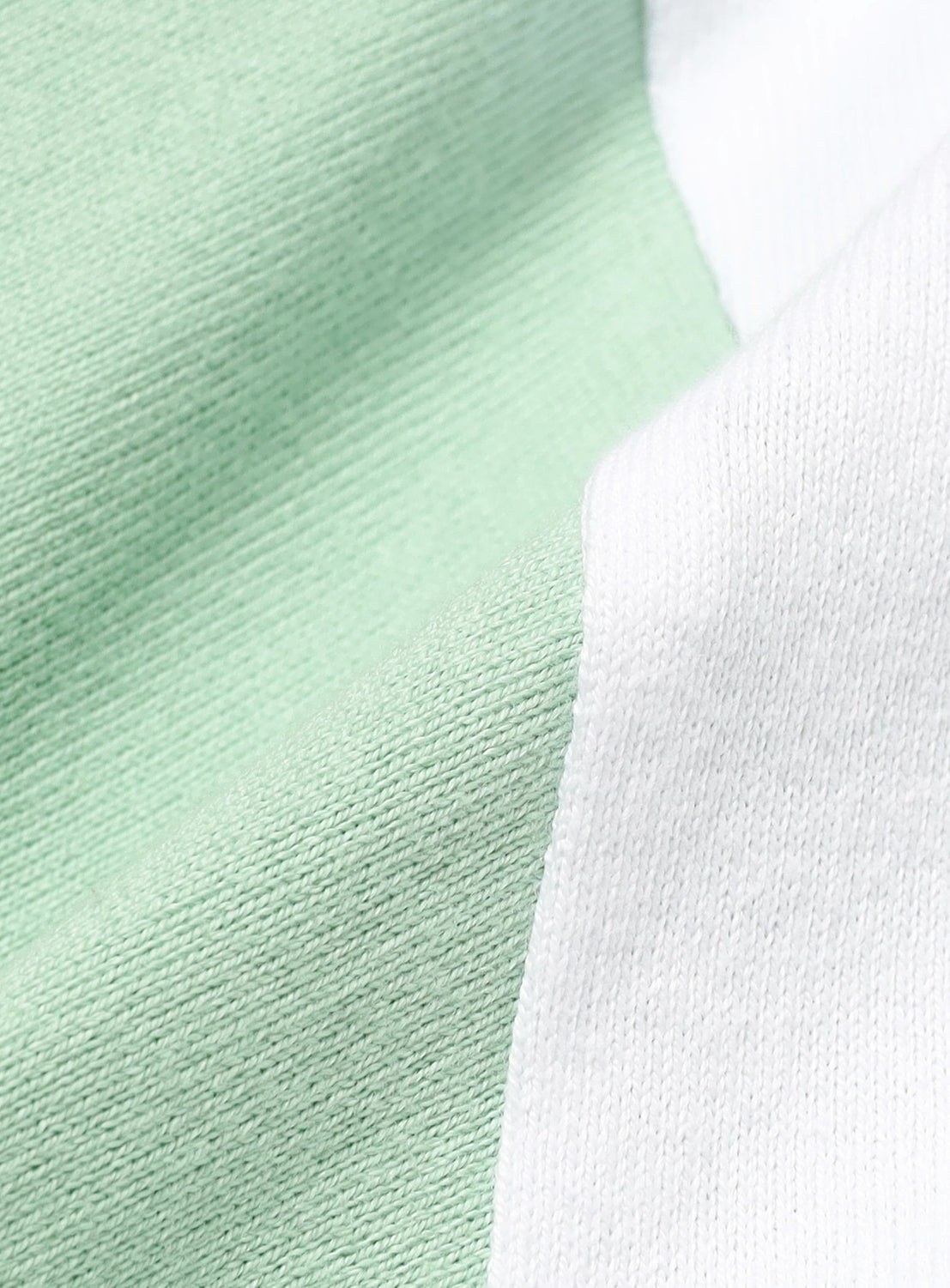 Close-up of a BEAMS Baseball 9/10 Sleeve T-Shirt featuring color-blocked panels of light green and white fabric.