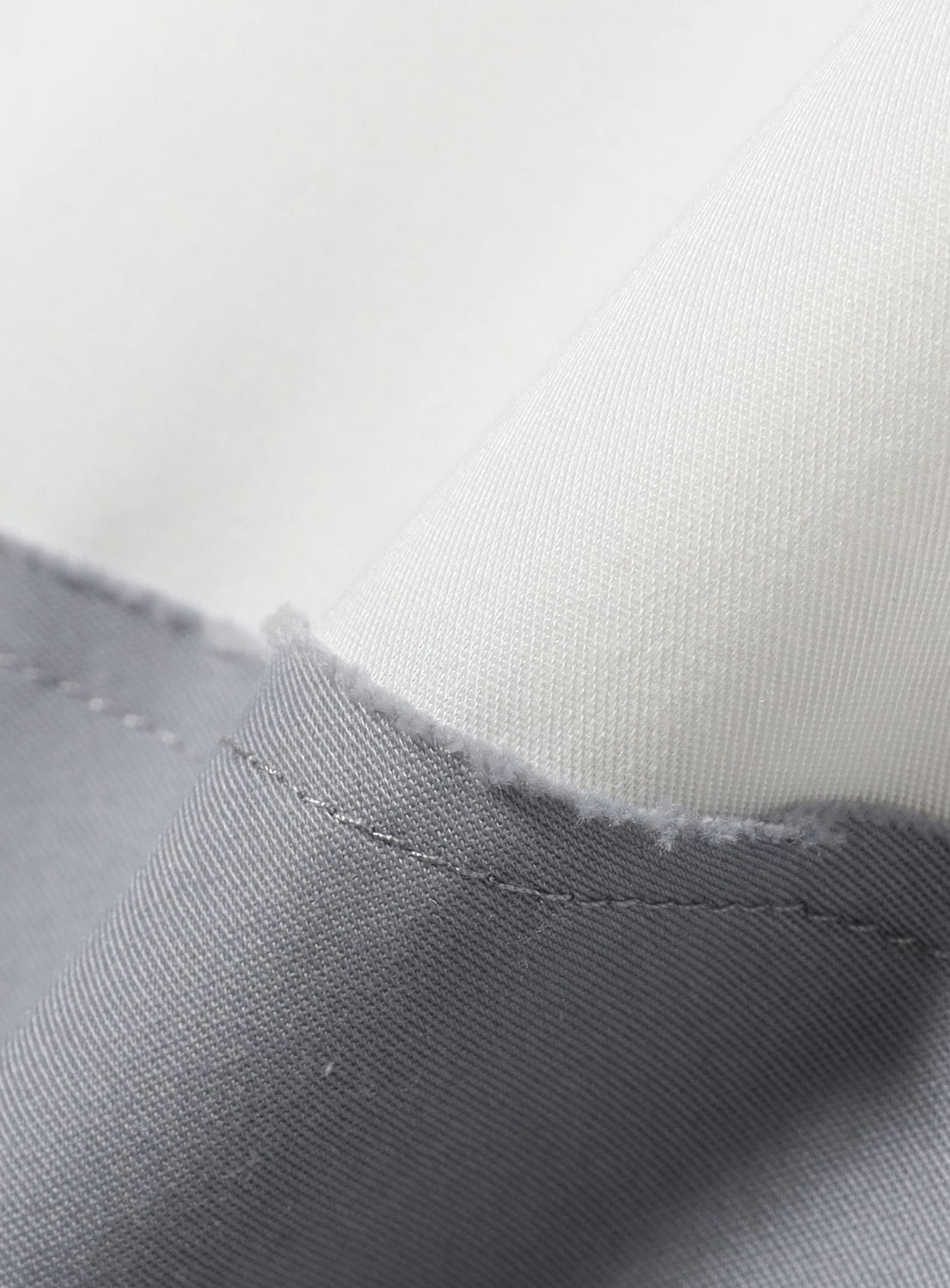 Close-up of gray fabric with stitching on a white background