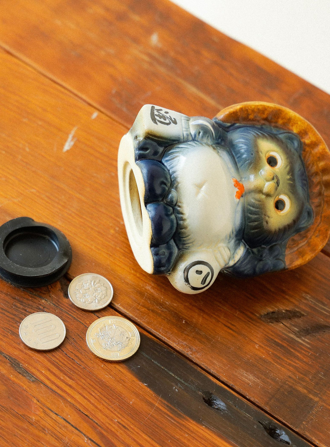 Decorative owl-shaped container with coins on a wooden surface