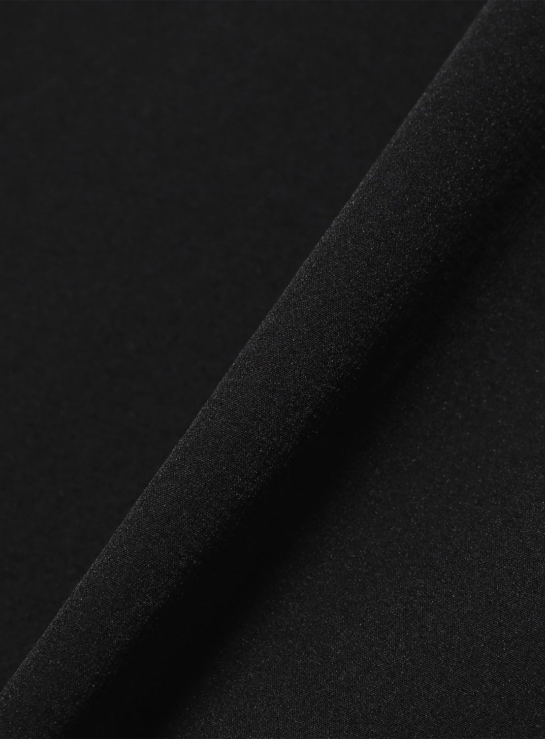 Close-up of a black Tech Shirt by BEAMS, showing the stretch fabric folded diagonally.