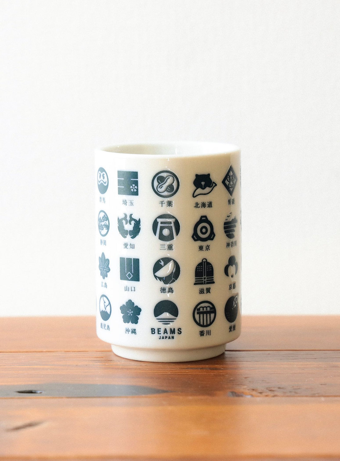 Ceramic mug with various symbols and branding on a wooden surface