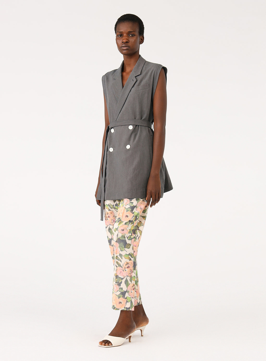 Model demonstrating the side silhouette of the grey sleeveless vest, emphasizing its longline cut.