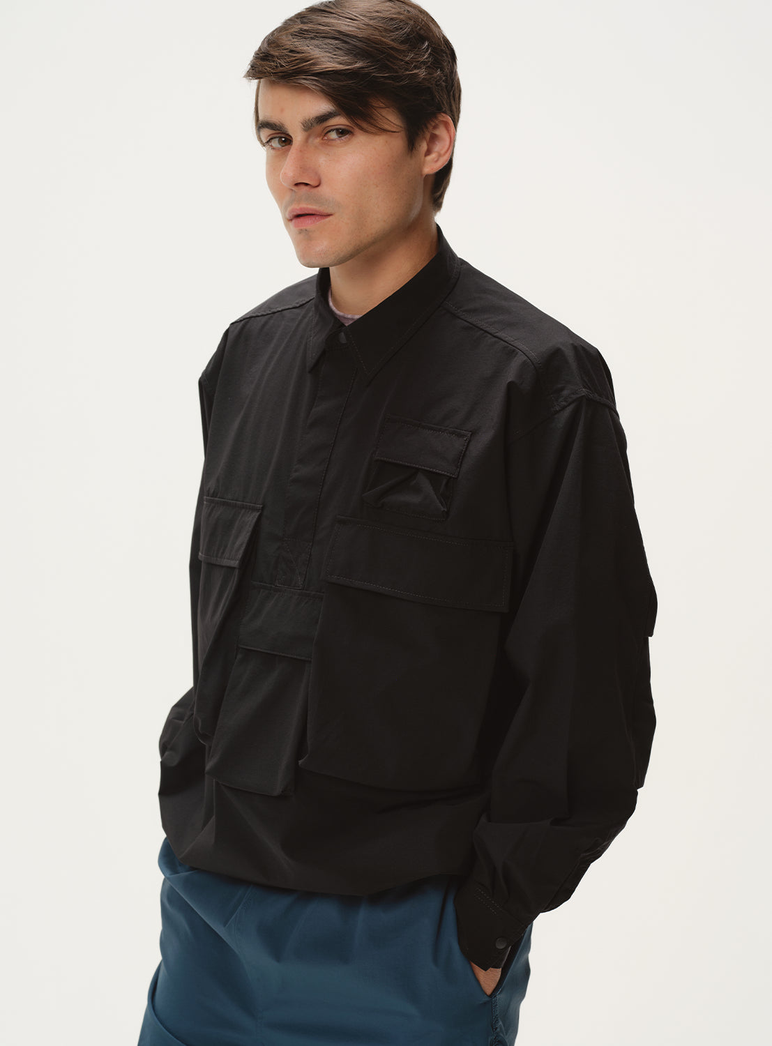 Full body shot of a model wearing a black shirt jacket, styled with blue pants.