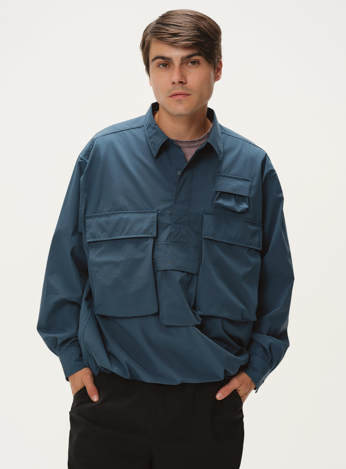 model wearing a dark teal shirt jacket, styled with black pants.