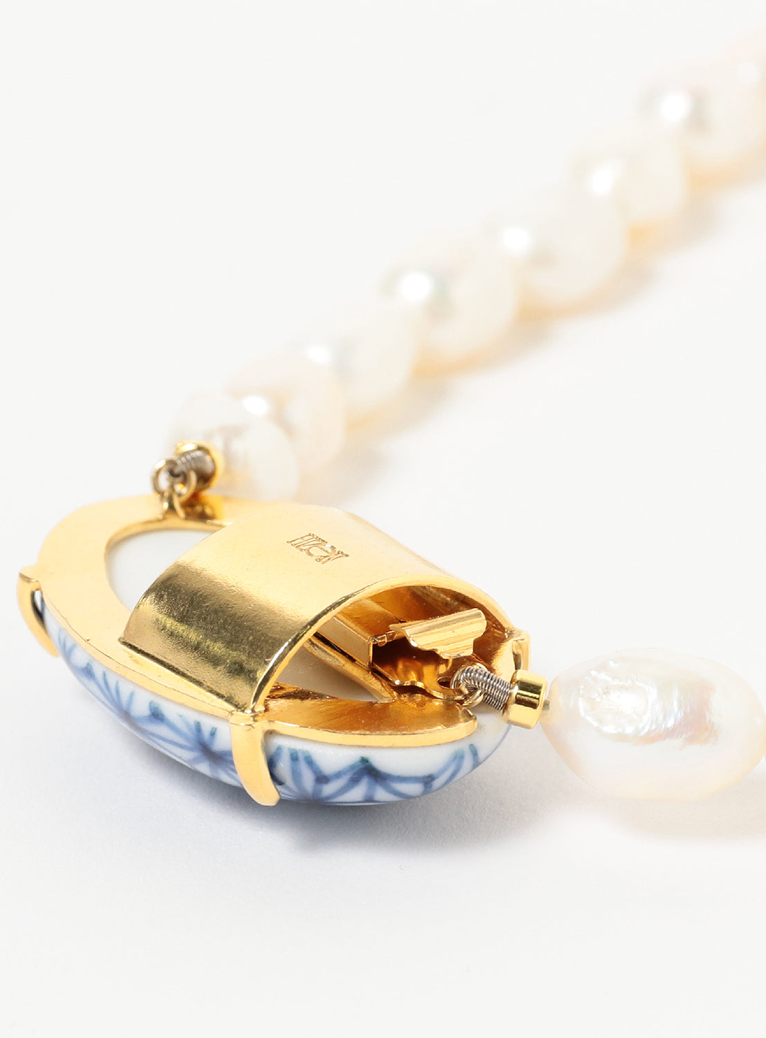 Close-up of the Hizen Jewelry Arita Ware Motif & Baroque Pearl Necklace - Small, featuring a gold clasp with blue and white ceramic details inspired by Arita porcelain necklace craftsmanship, attached to a strand of baroque freshwater pearls, partially fastened against a white background.