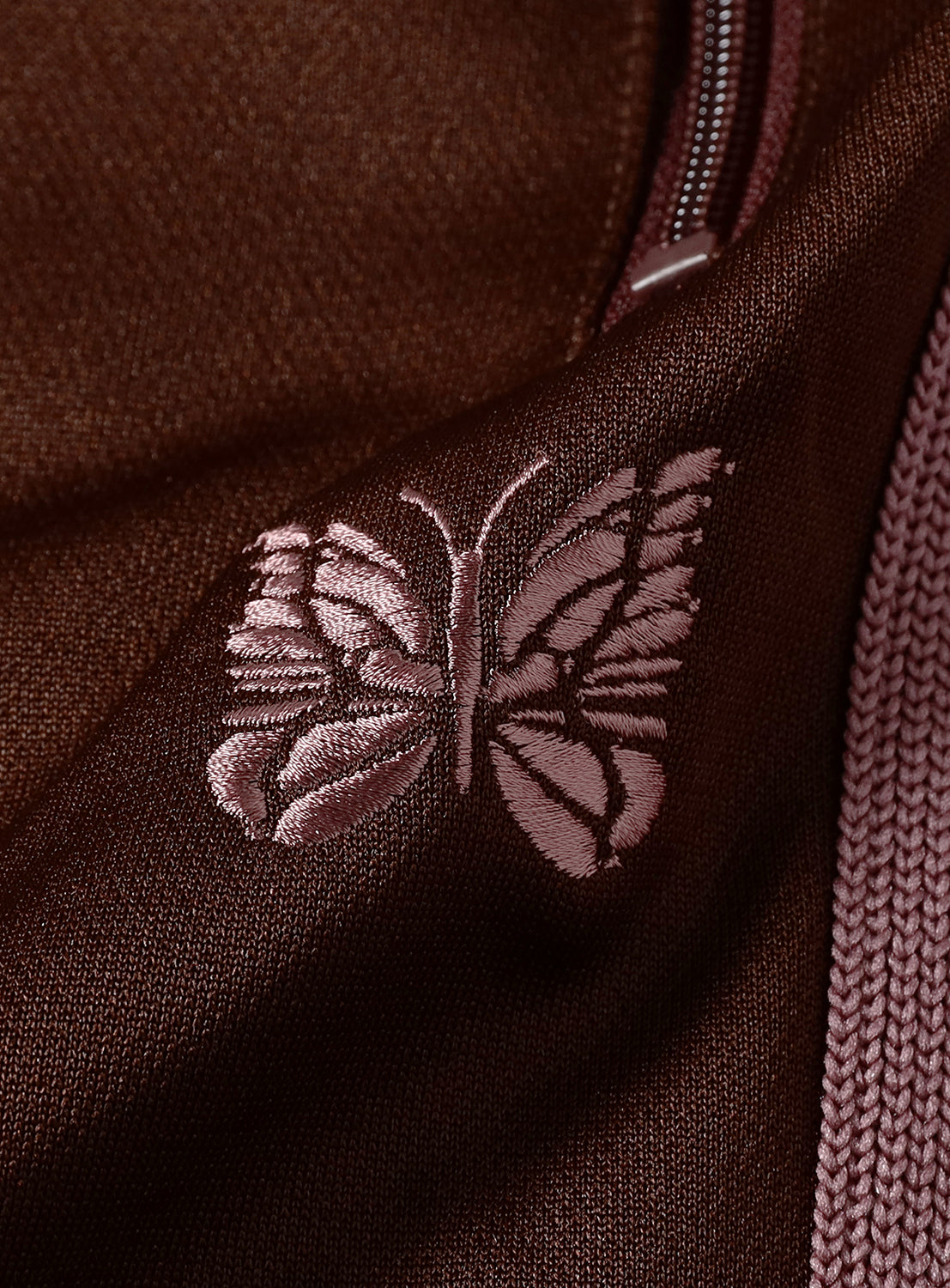 Close-up of a brown/burgundy fabric with a pink embroidered butterfly design.