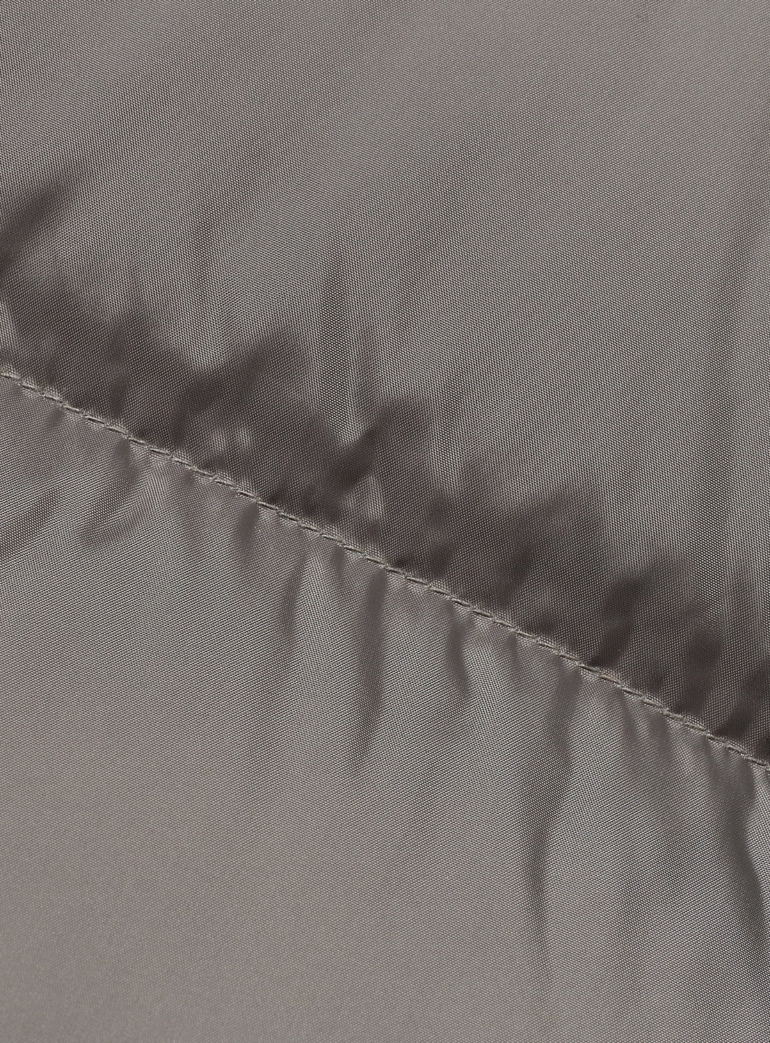 Close-up of the reversible side of a gray fabric with stitching detail.