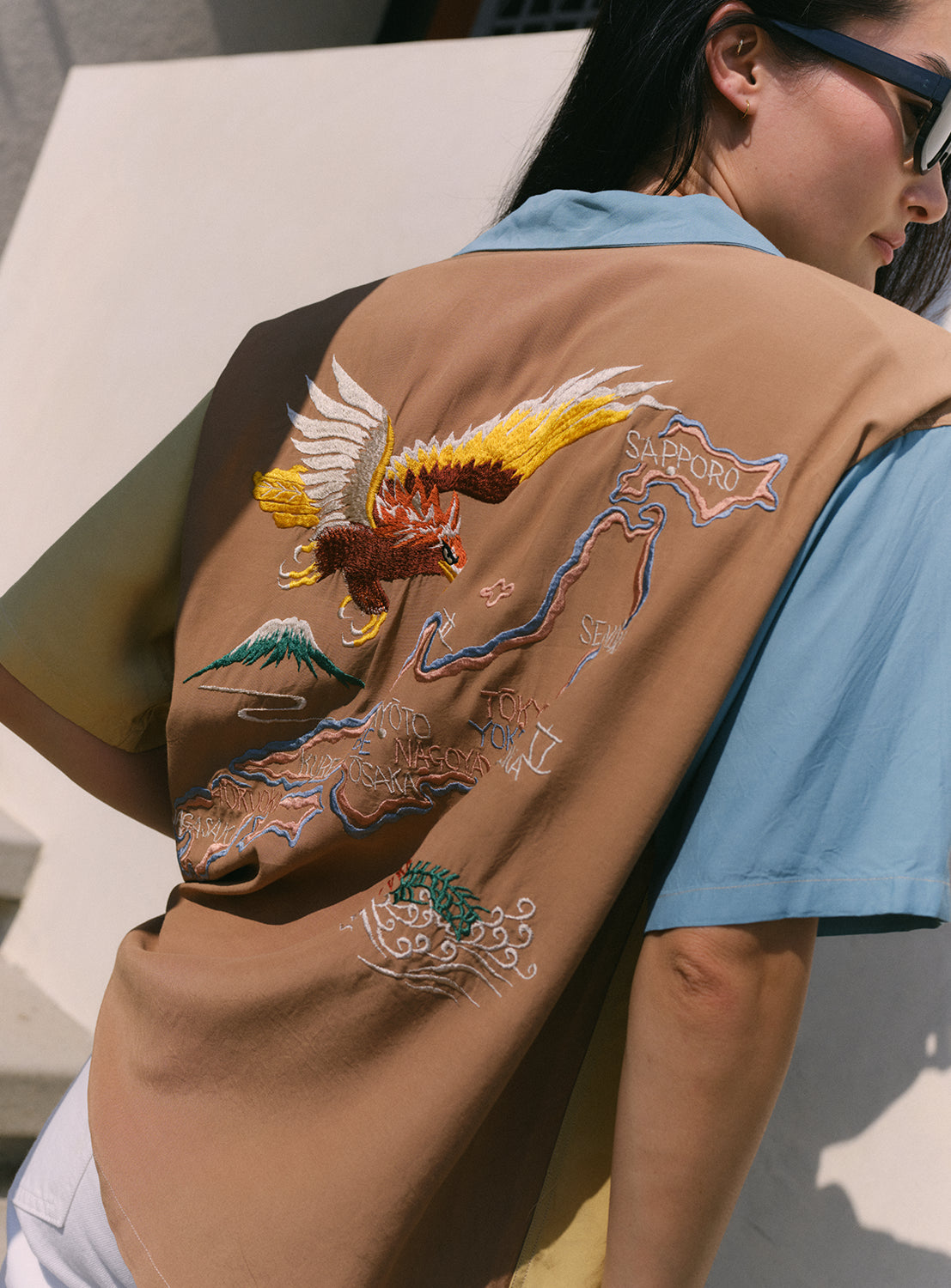Back of teal, beige, and brown color block button shirt with an eagle and a dragon facing Japan. 