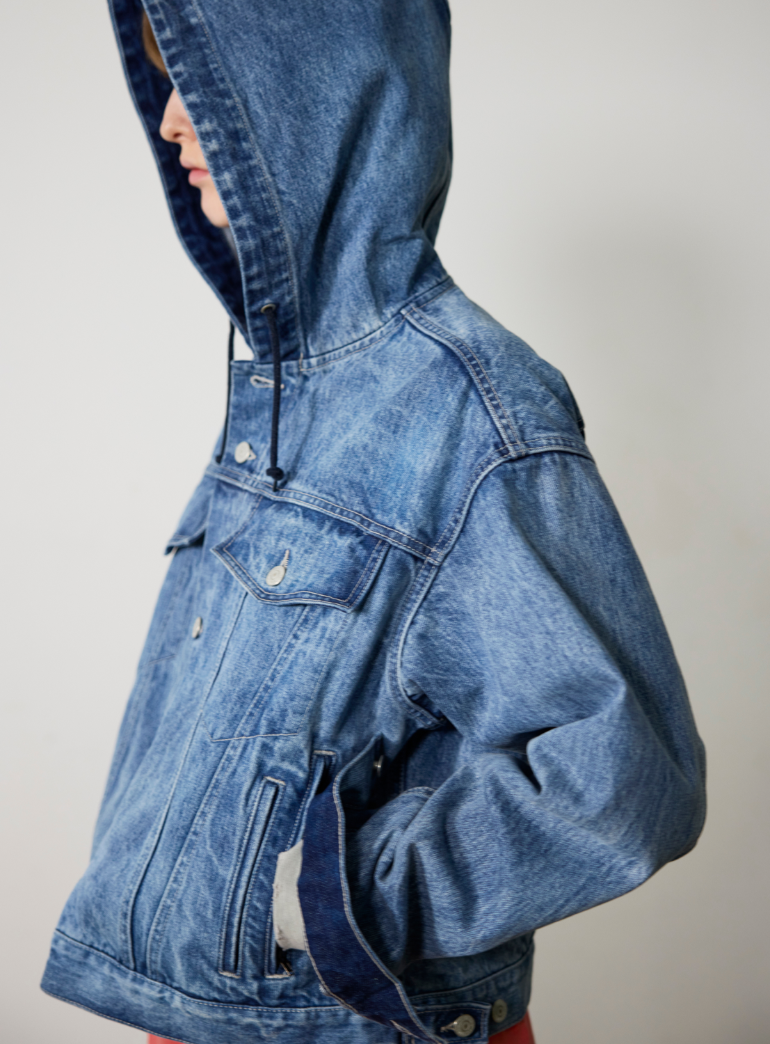 Side profile of a person wearing a BEAMS Hooded Trucker Denim Jacket.