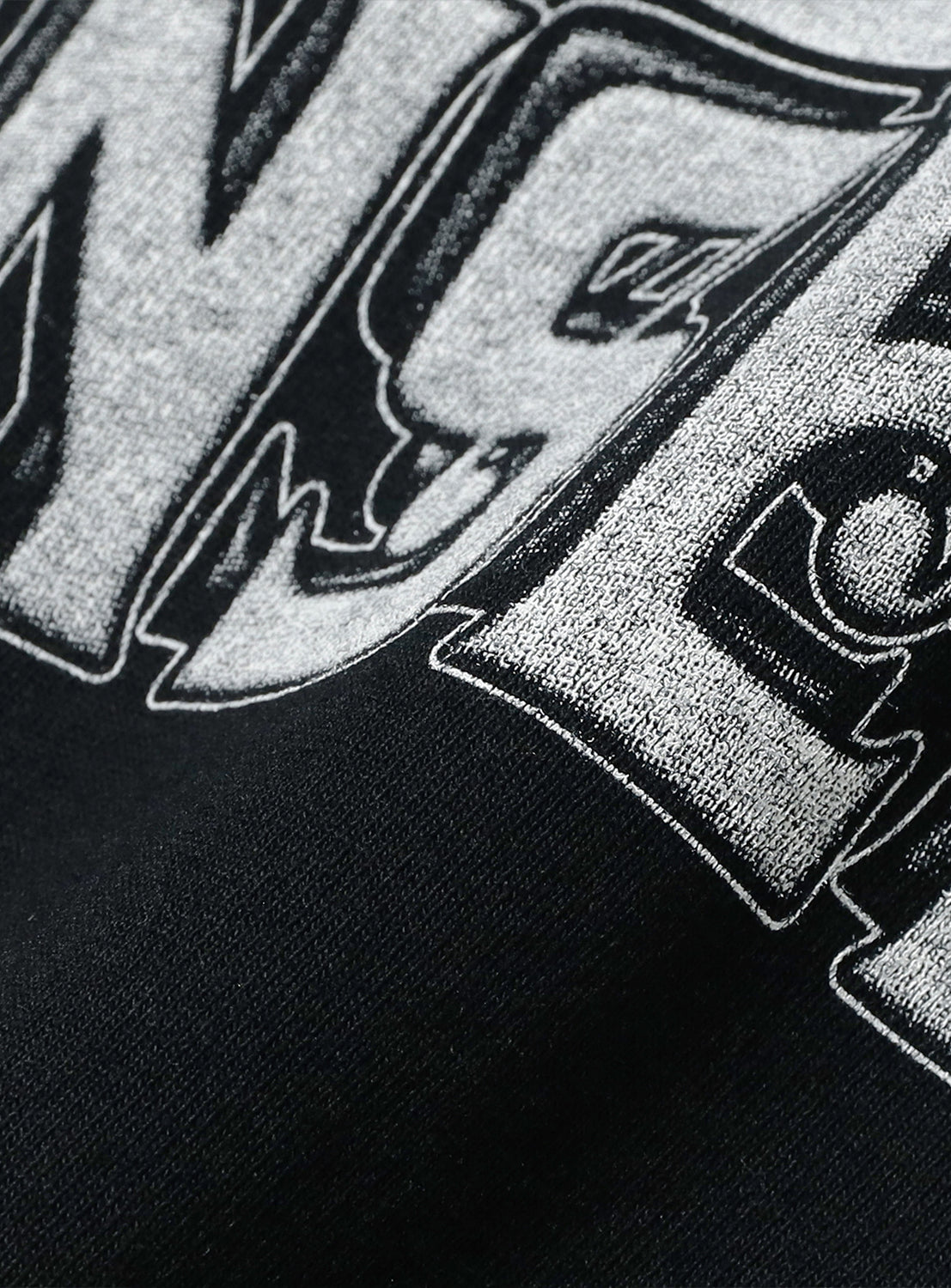 Close-up of black t-shirt fabric, detailing the white/grey graphic print and distressed texture.