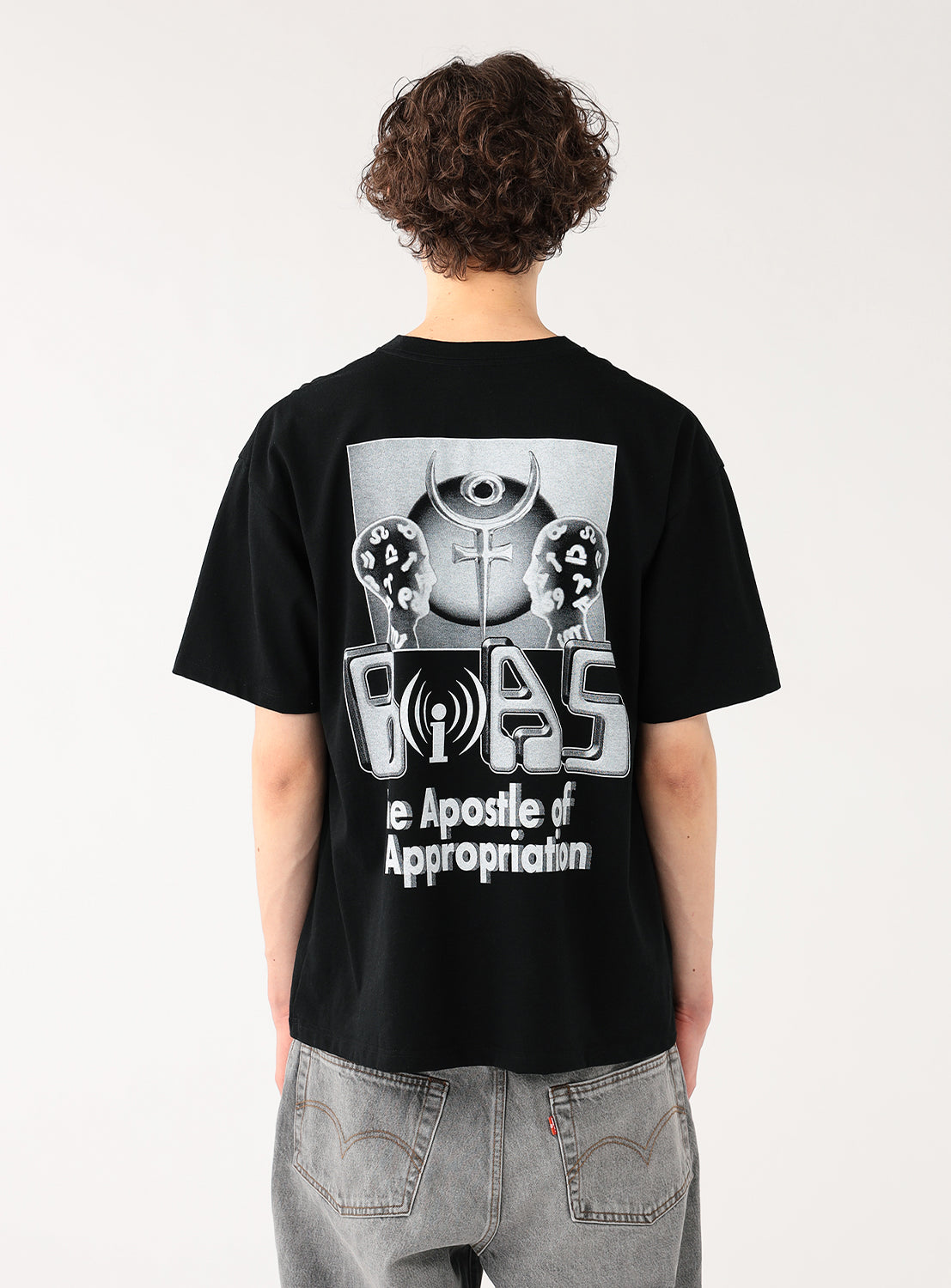 Model wearing a black t-shirt, back view, highlighting the white/grey abstract graphic print and text.