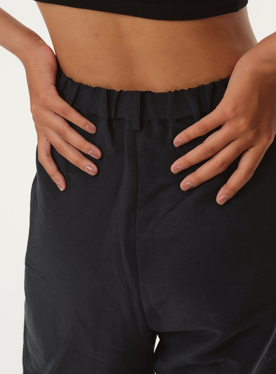 Close-up of a model's waist from the back, showing the cinched elastic waistband of the navy pants.