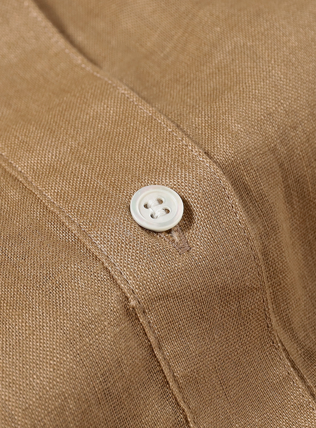 Close-up of a white button on the beige material. 