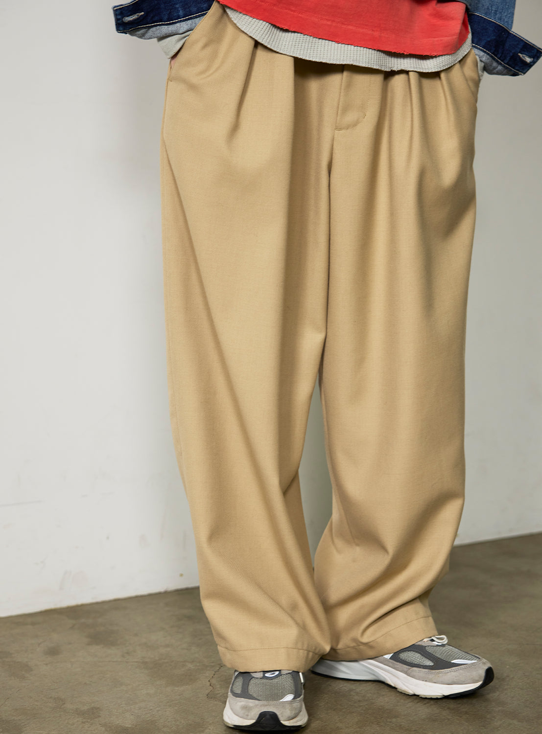 BEAMS Chambray Chino Pants in a beige, wide straight fit with pleats, worn with grey athletic sneakers.