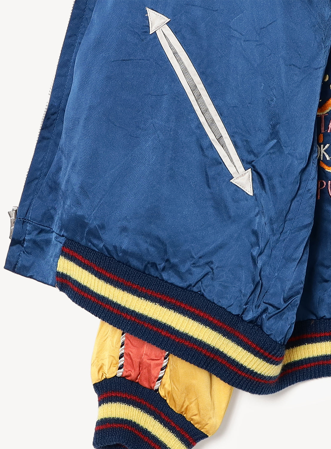 Close-up of the TAILOR TOYO Late 1940s Style Acetate Souvenir Jacket KOSHO & CO. Special Edition “EAGLE & DRAGON” × “JAPAN MAP” in blue, with a diagonal white arrow pocket design, yellow/navy ribbed cuffs, and a hint of yellow lining.