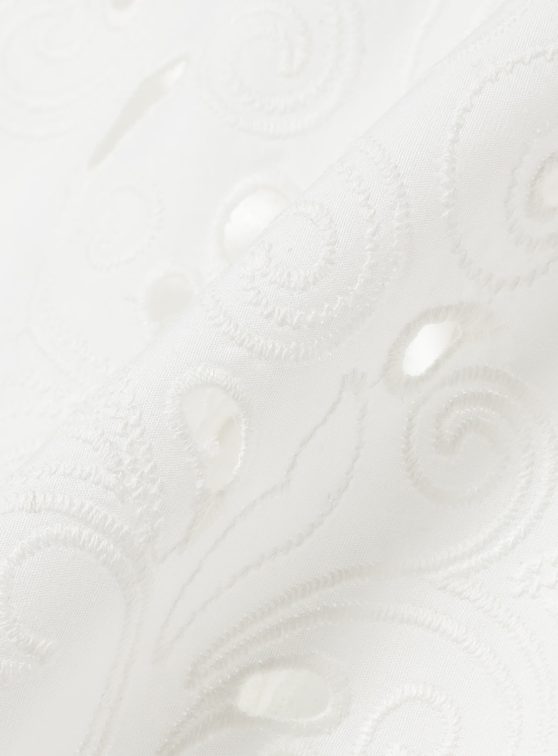 Close-up of the white blouse fabric, highlighting the intricate leaf-patterned cutwork embroidery.