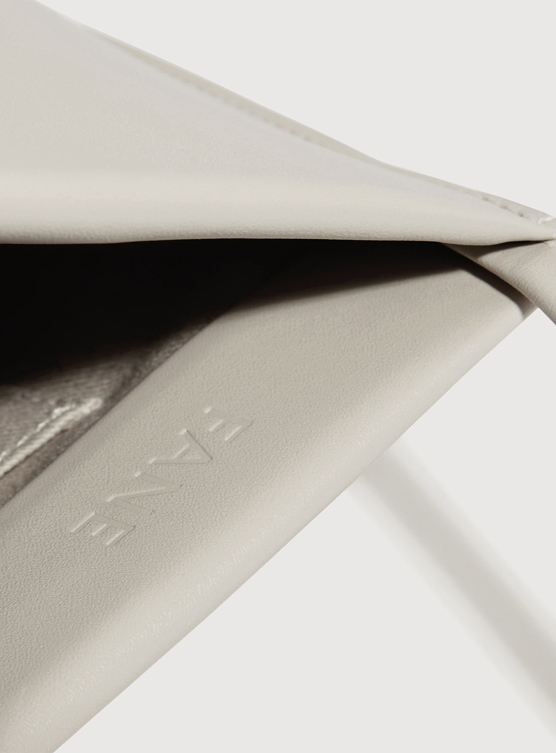Close-up of a beige leather shoulder bag with 'FANE' branding imprinted on the inside. 