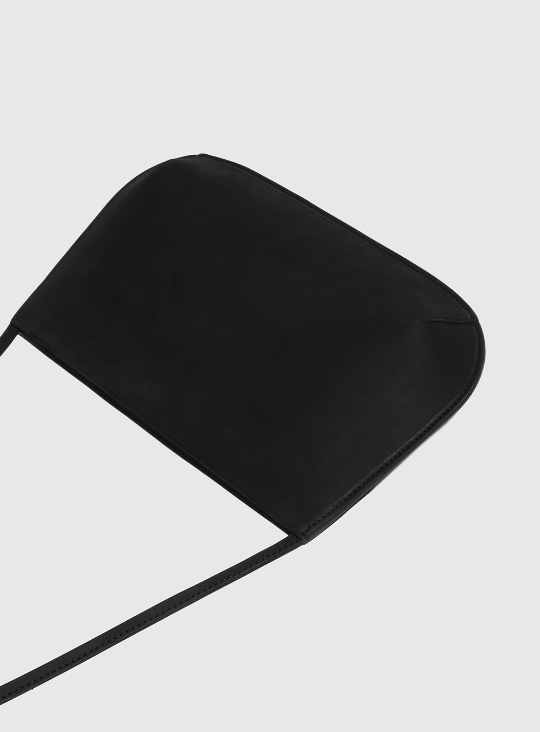 Black ultra-slim, curved silhouette shoulder bag laid flat. 