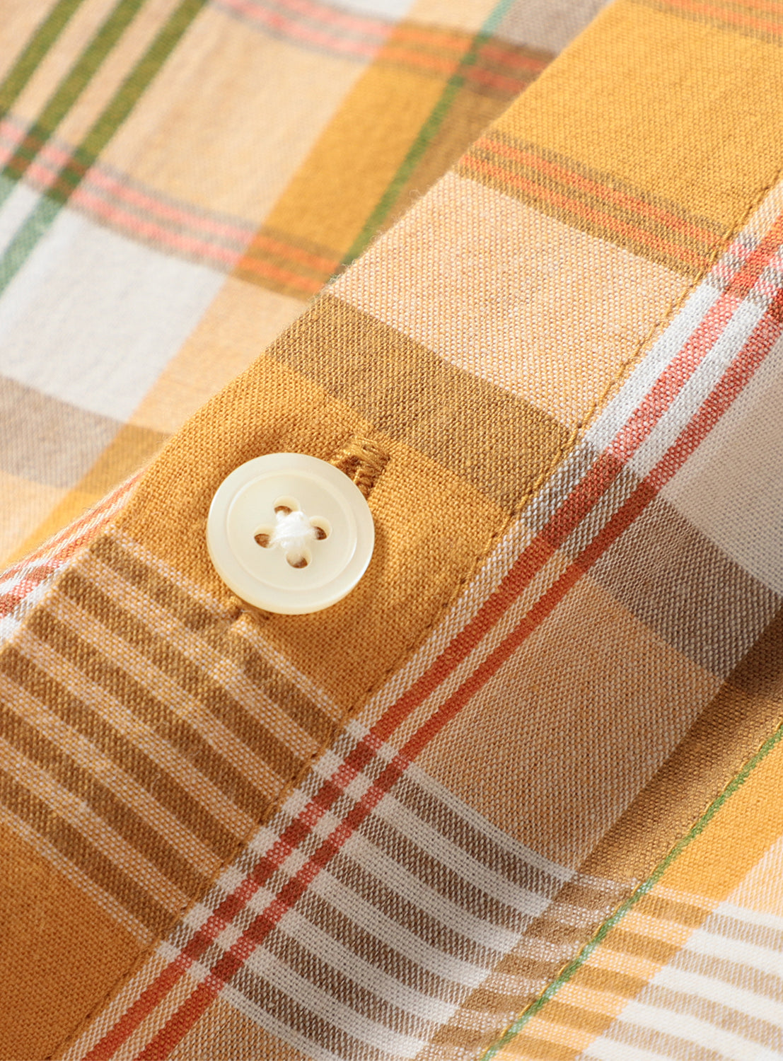 Close-up of orange with green and orange striped check shirt fabric and button, detailing the breathable cotton texture.