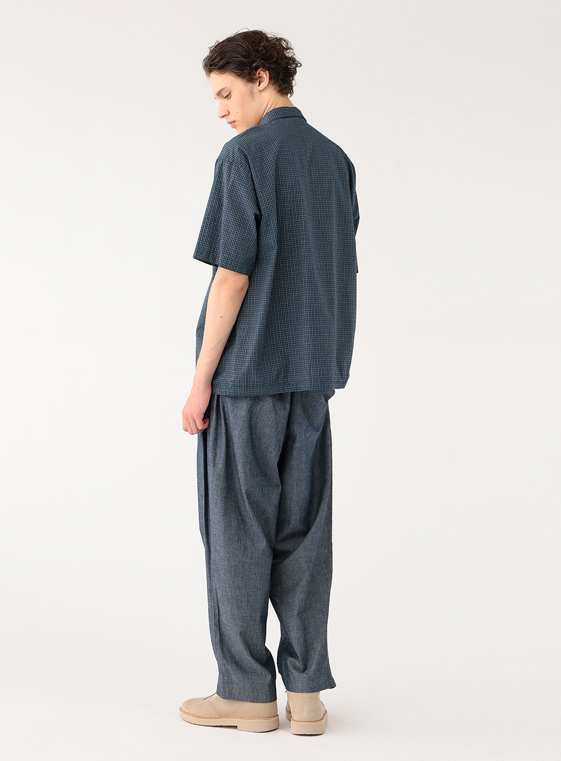 Model wearing a navy blue check-patterned pullover shirt, back view, demonstrating effortless drape.