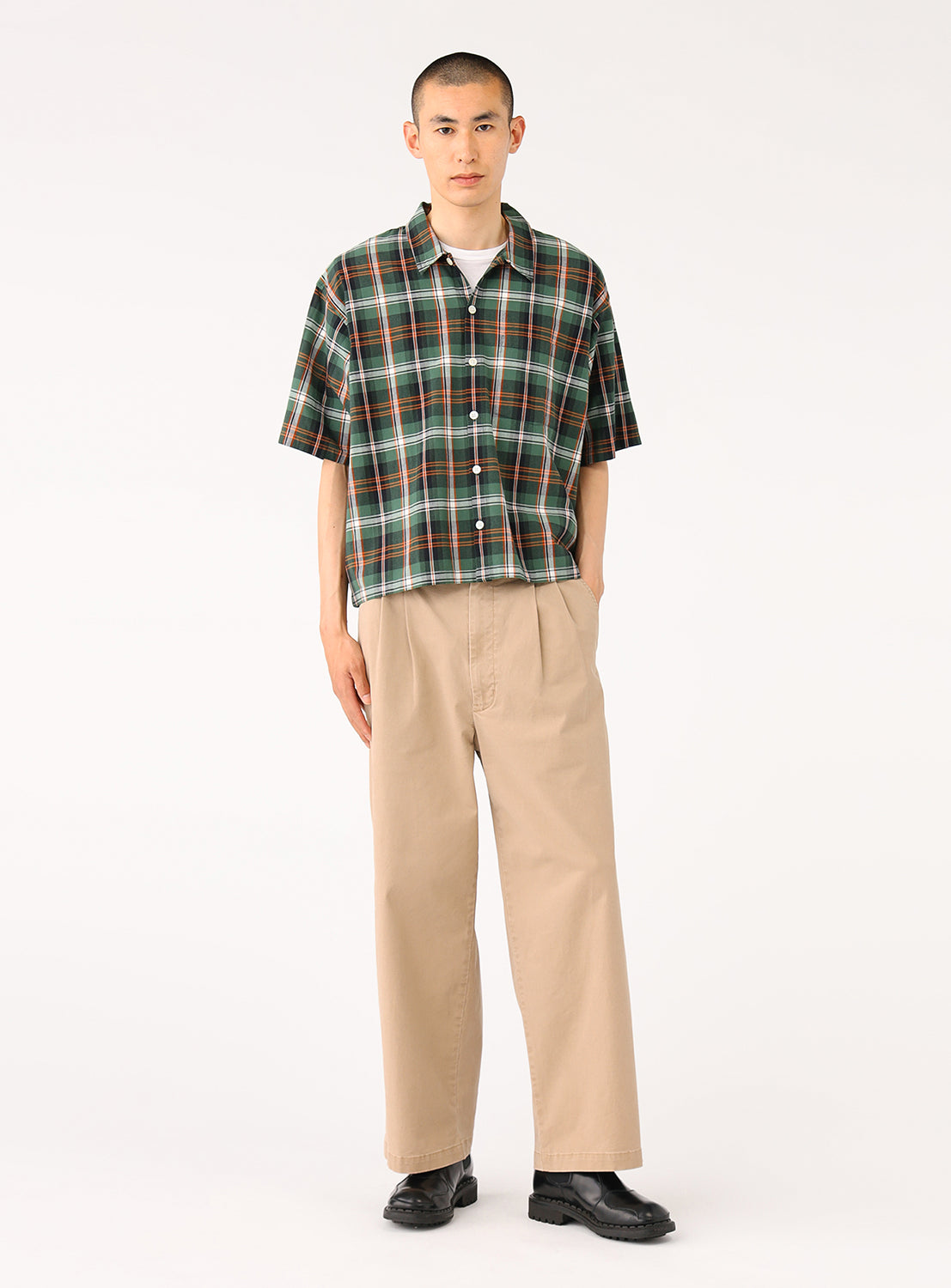 Model wearing a green cropped-length check shirt, side view, showing relaxed silhouette.