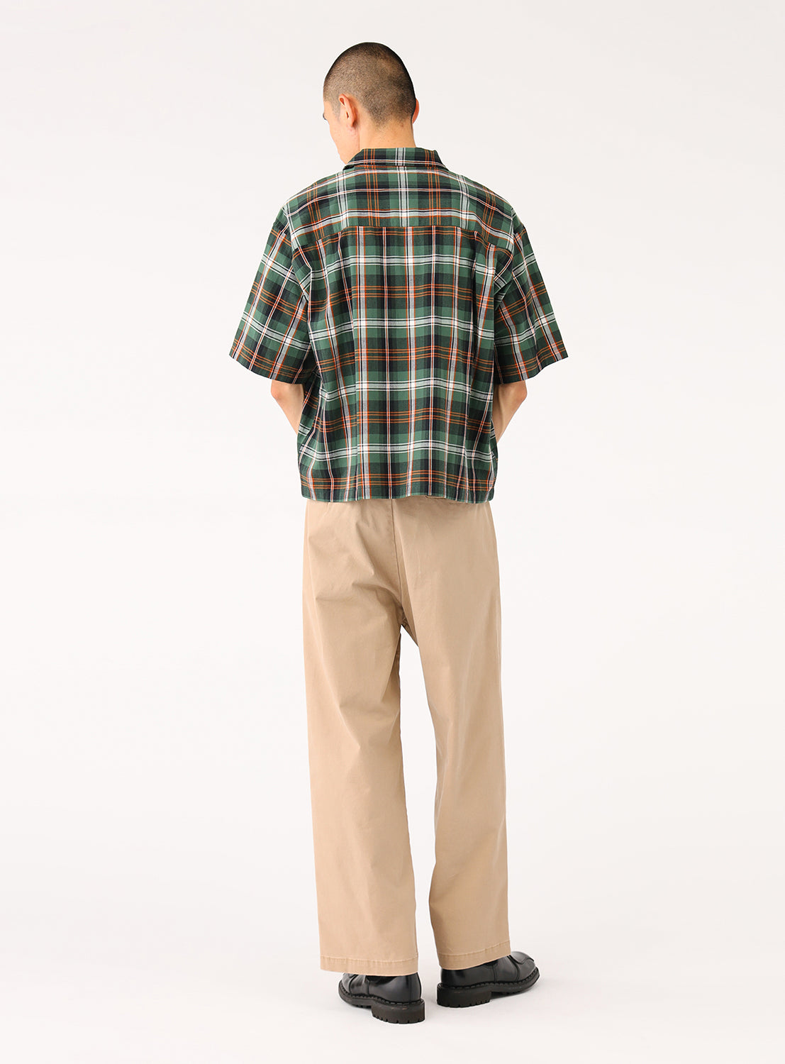 Model wearing a green and black cropped-length check shirt, back view, made from breathable 100% cotton.