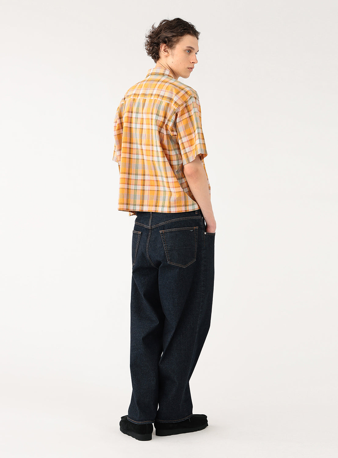 Model wearing an orange with green and orange striped cropped-length check shirt, back view, crafted from breathable cotton.