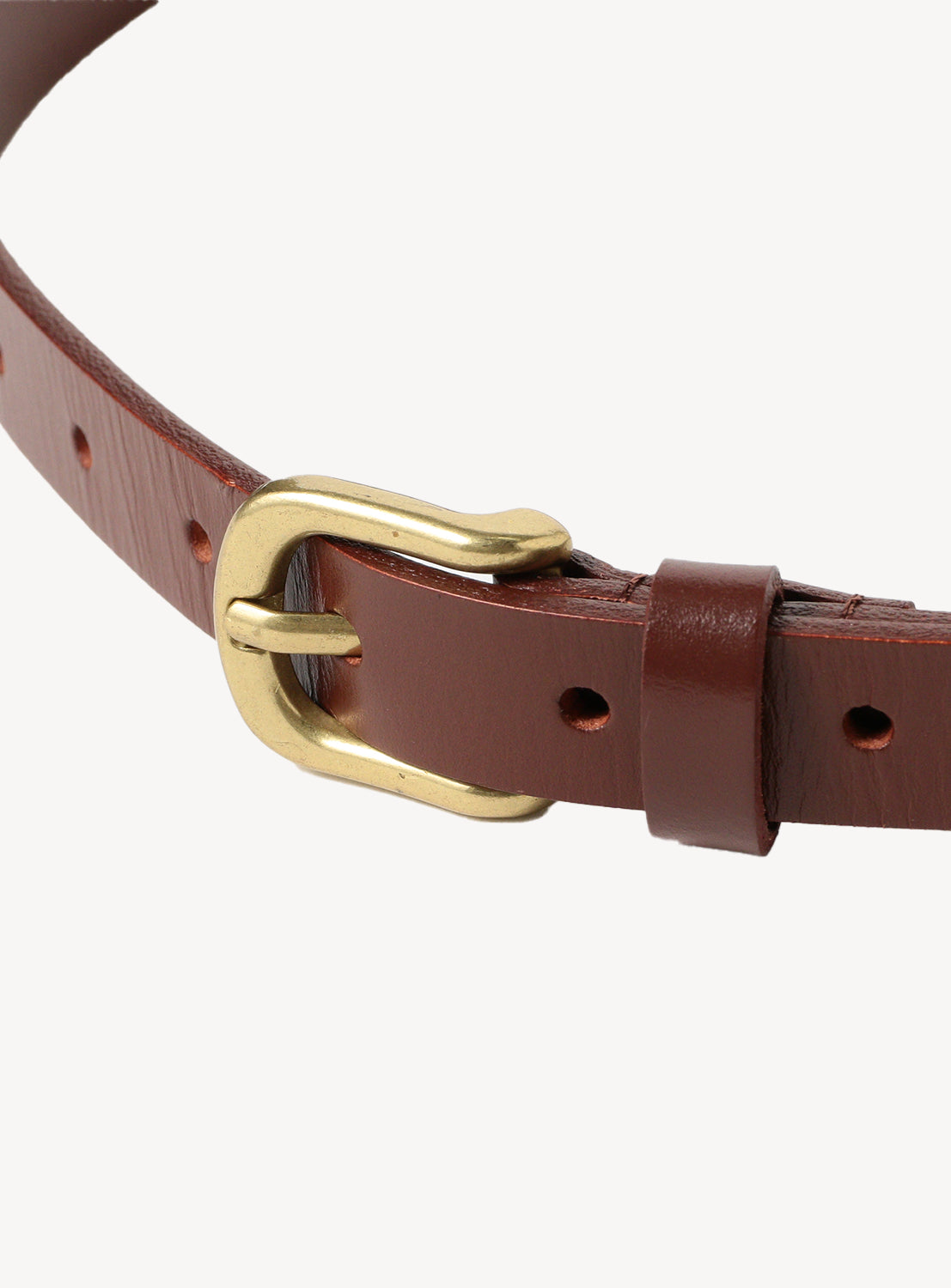 Close-up of a brown leather belt with a rectangular brass buckle and buckle holes.