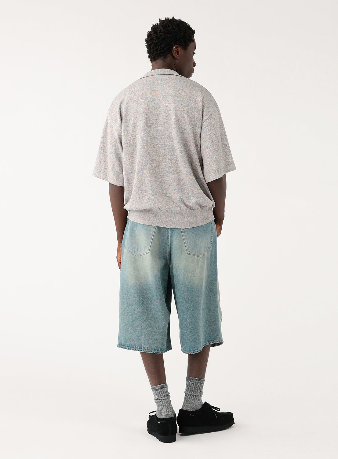 Male model from behind, wearing a light grey, short-sleeved collared shirt.