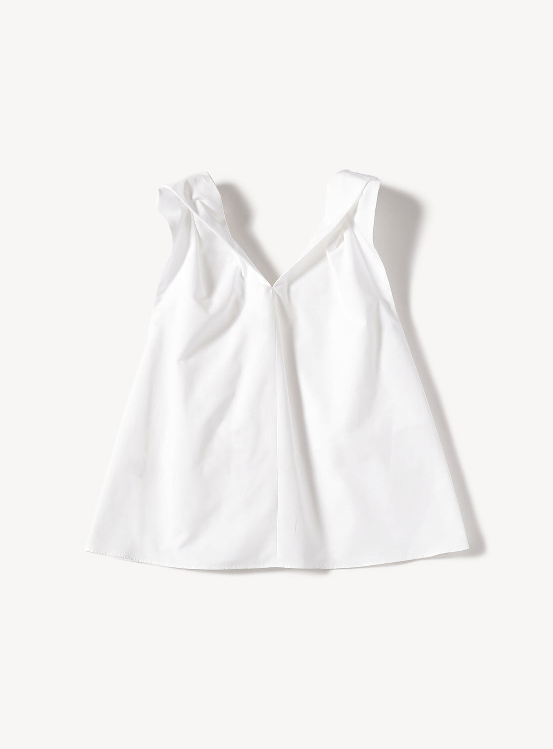 White sleeveless top with a deep V-neck and ruffled shoulder straps.