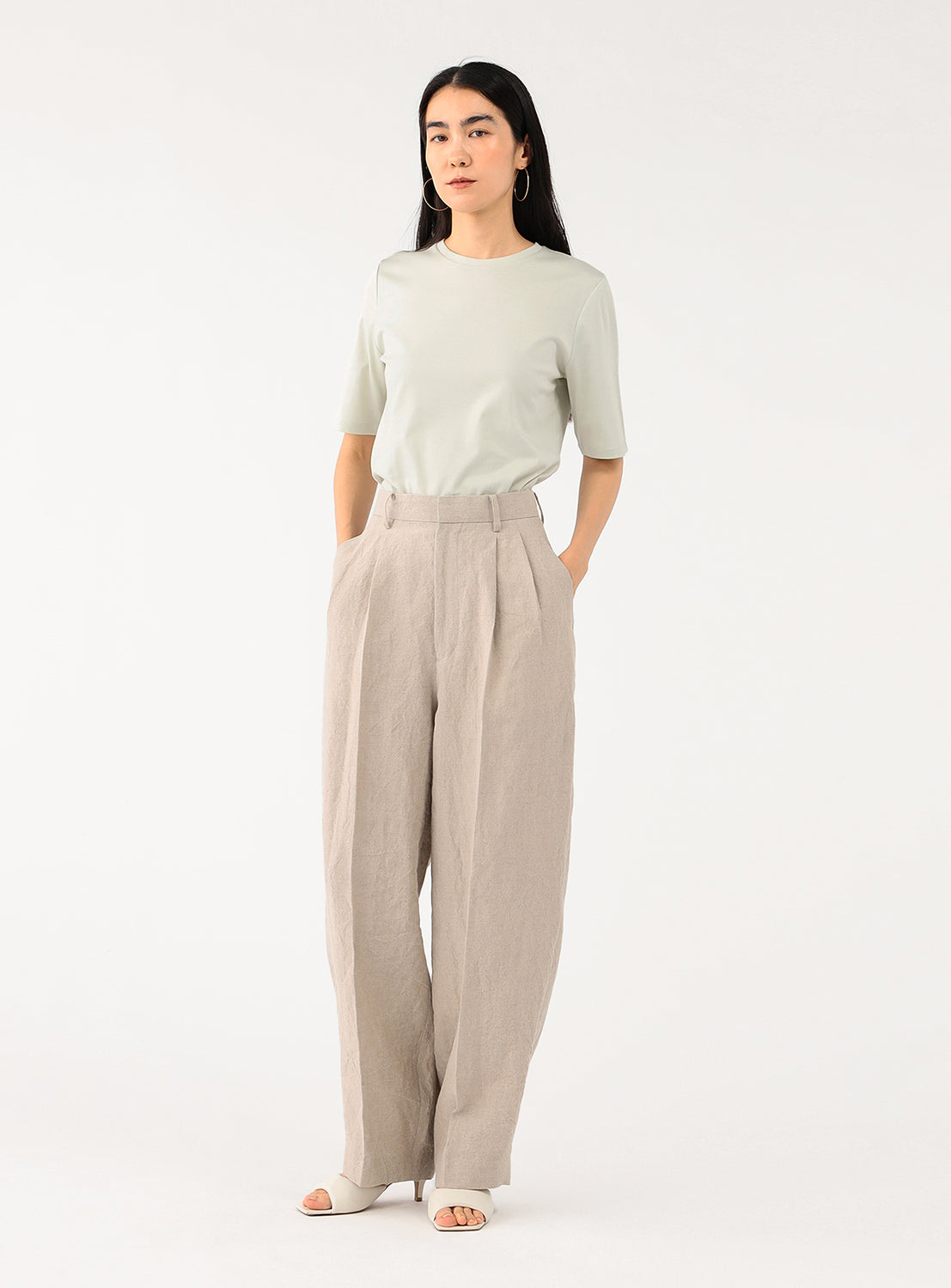 Model showcasing a styled outfit, featuring a simple crew neck t-shirt and wide-leg trousers.