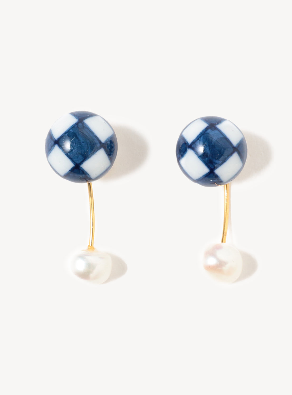 Introducing the Arita Ware Motif & Baroque Pearl Earrings by Hizen Jewelry: a stunning pair featuring round blue and white checkered tops crafted from exquisite Arita porcelain, graceful gold curved stems, and elegant freshwater pearls. Photographed on a plain light background, these earrings beautifully showcase the artistry of Japanese craftsmanship.